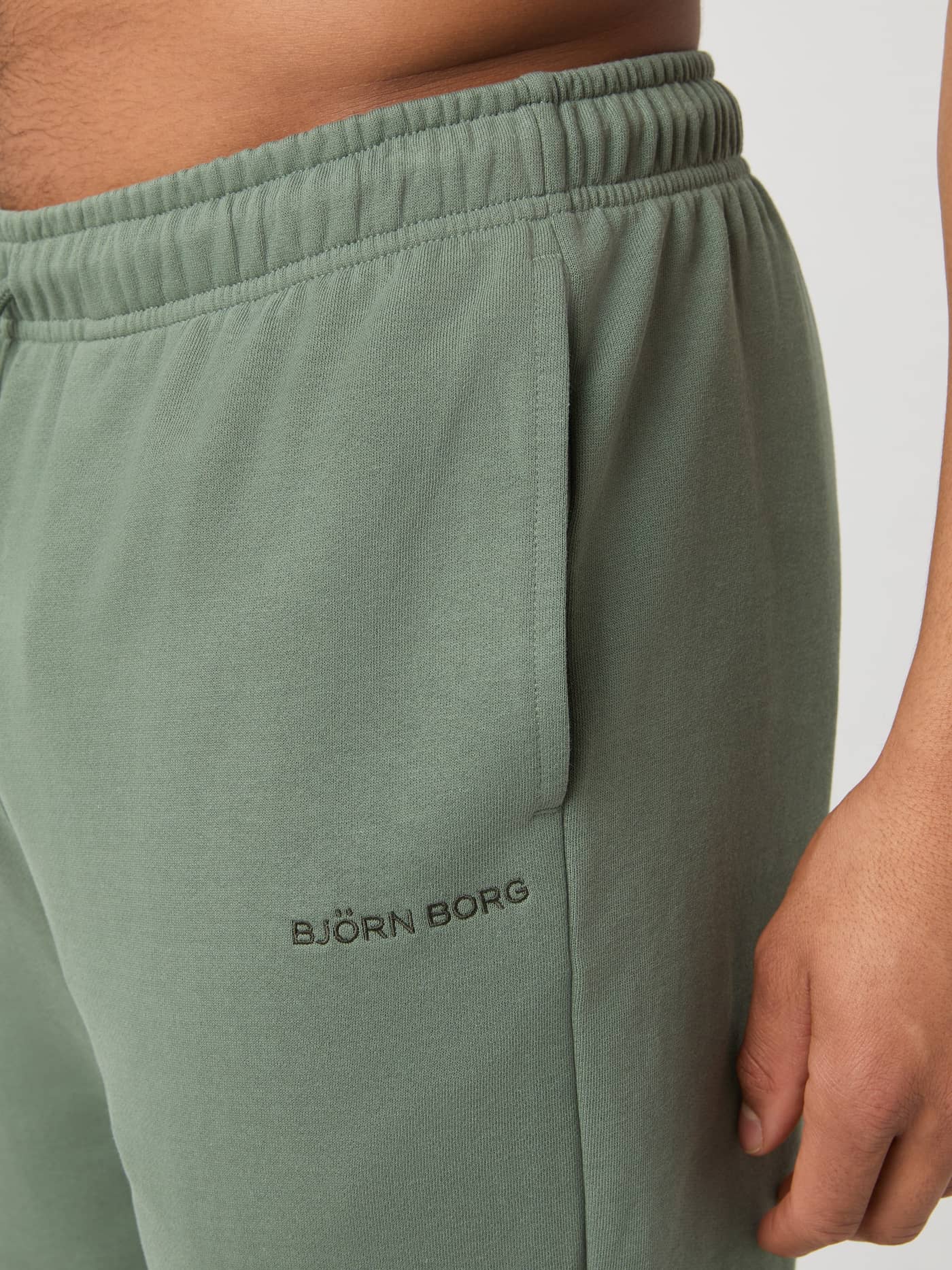 Close-up van de functionele zijzak en het donkere logo op de katoenen Borg Classic Sweatpants in Agave Green (Groen). - Image 3