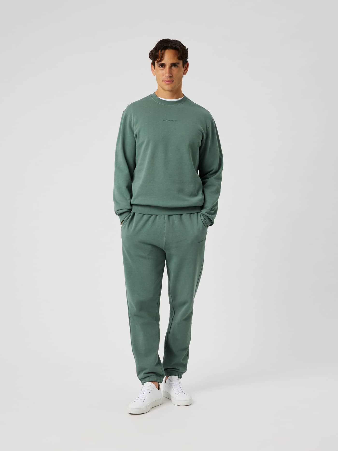Front view of a model wearing Borg Classic Sweatpants in Laurel Wreath (green) with side pockets and ribbed cuffs. - Image 3