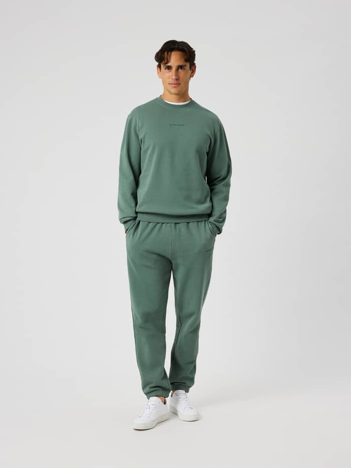 Front view of a model wearing Borg Classic Sweatpants in Laurel Wreath (green) with side pockets and ribbed cuffs.
