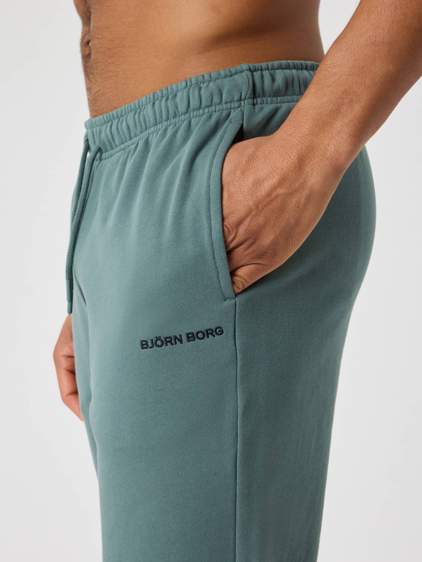 Sidovy på man i Borg Classic Sweatpants i Balsam Green (Grön) av bomull med sidoficka och en svart logotyp. - Image 4