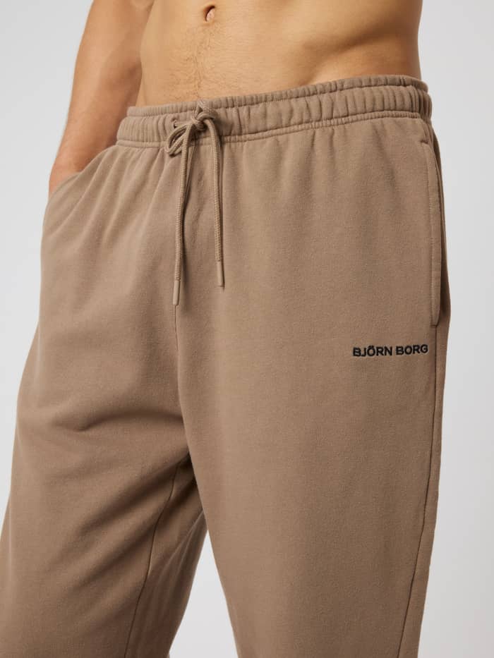 Close-up van de katoenen Borg Classic Sweatpants in Caribou (Bruin) met een zwart geborduurd logo en trekkoord. - Image 5