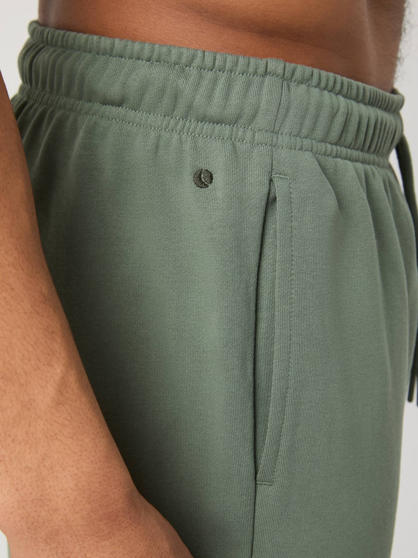 Detail van de katoenen Borg Classic Sweatpants in Agave Green (Groen) met een zijzak en donkergroen logo. - Image 4