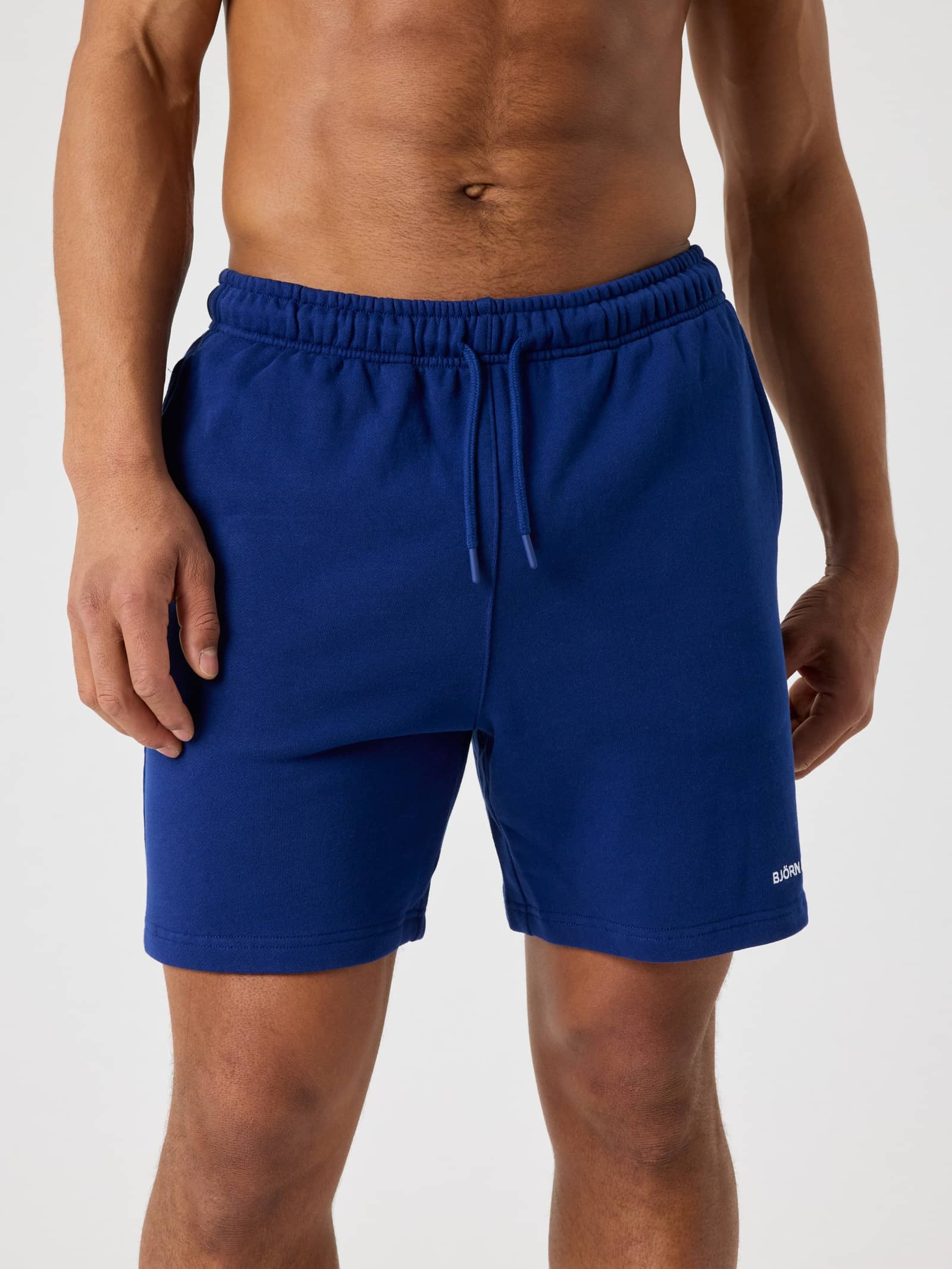 Vue de face d'un homme portant le Borg Classic Sweatshorts en coton Blue Depths (Bleu) avec un logo blanc. - Image 1
