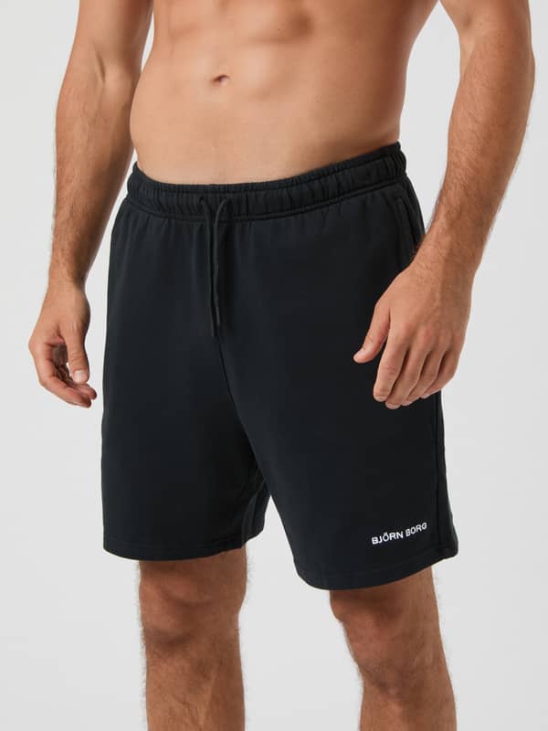 Front view of a man wearing cotton Borg Classic Sweatshorts in Black Beauty (Black) with a white logo for training.