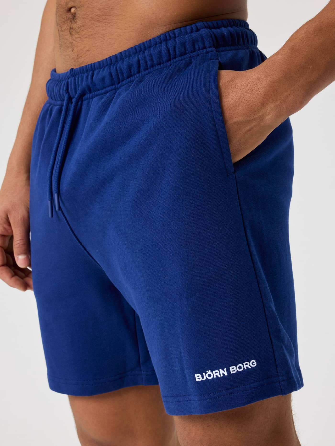 Close-up of a man wearing Blue Depths (Blue) Björn Borg Classic Sweatshorts in cotton French terry with a white logo. - Image 4