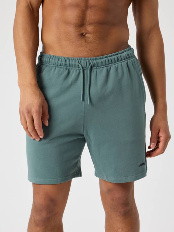 Front view of a man wearing the cotton Borg Classic Sweatshorts in Balsam Green (Green) with a black logo and drawstring.