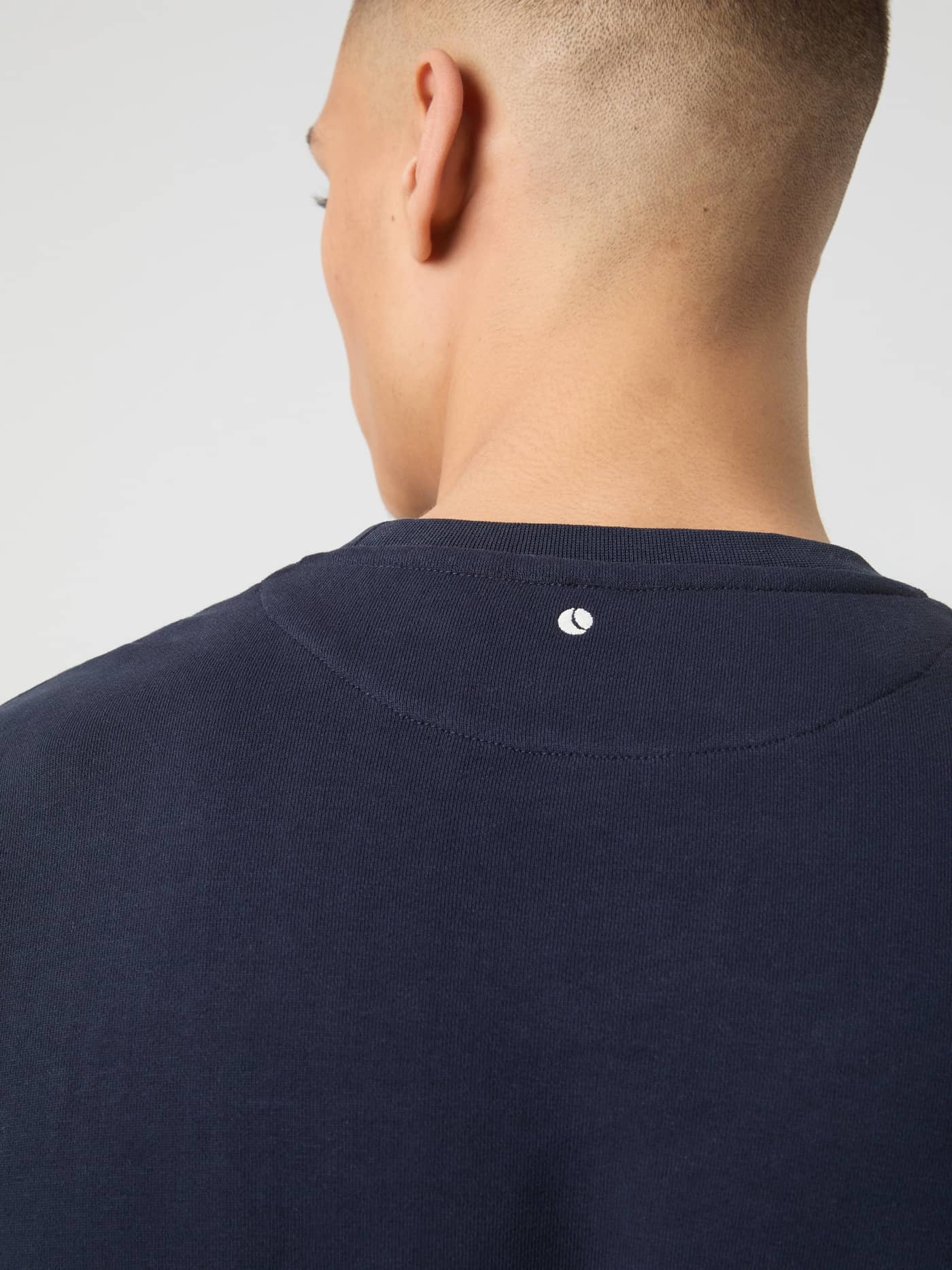Back neck detail of the cotton Borg Classic Sweatshirt in Night sky (Navy) with a white tennis ball logo. - Image 4