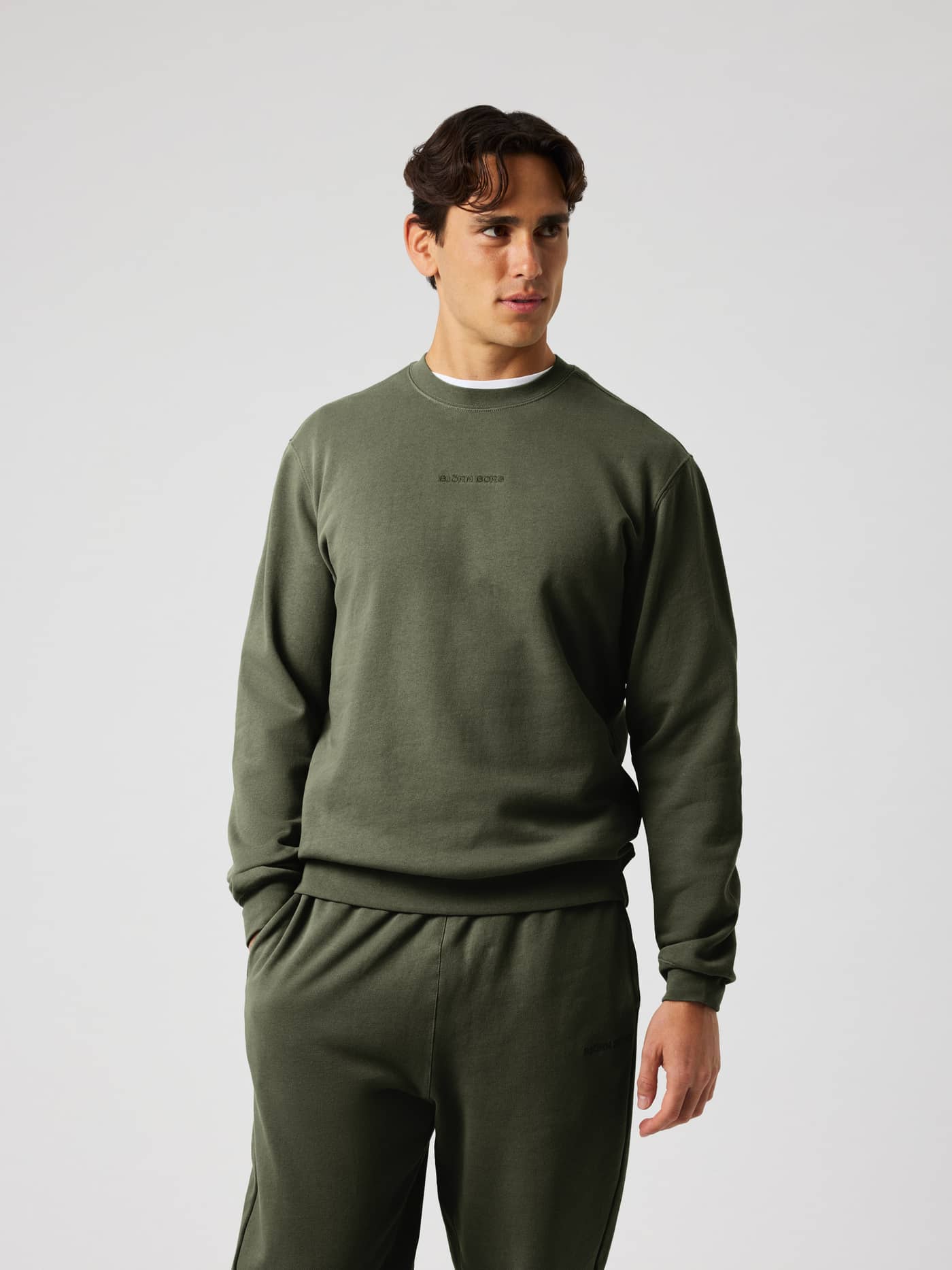 Front view of a man wearing the Borg Classic Sweatshirt in Rosin (Green) with a tonal logo on the chest. - Image 2