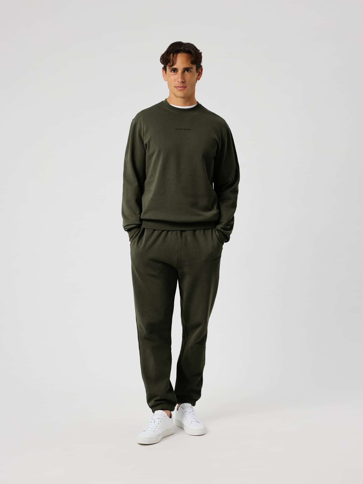 Full-body front view of a man in the cotton Borg Classic Sweatshirt in Rosin (Green) featuring a black logo. - Image 4