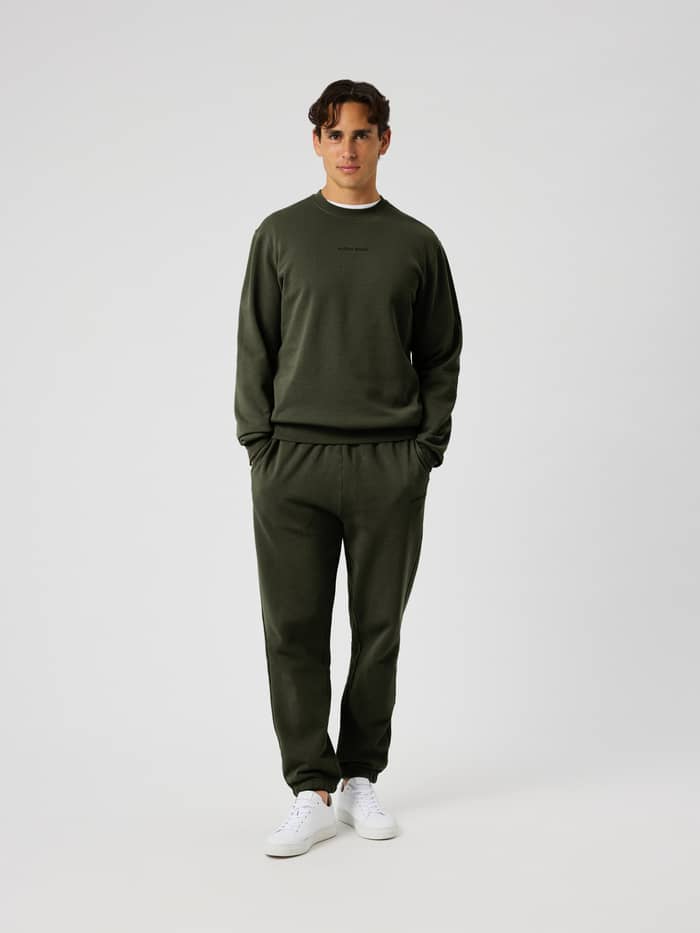 Volledig vooraanzicht van een man in het katoenen Borg Classic Sweatshirt in Rosin (Groen) met een zwart logo. - Image 4