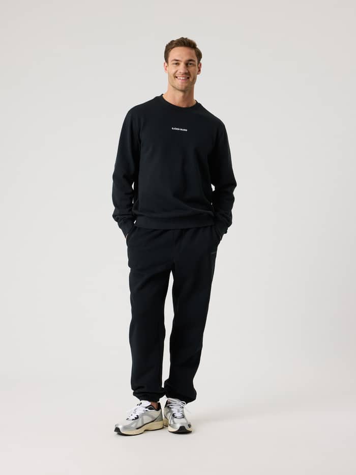 Vue de face d'un homme en pied portant le Borg Classic Sweatshirt Black Beauty (Noir) en coton avec un logo blanc. - Image 3