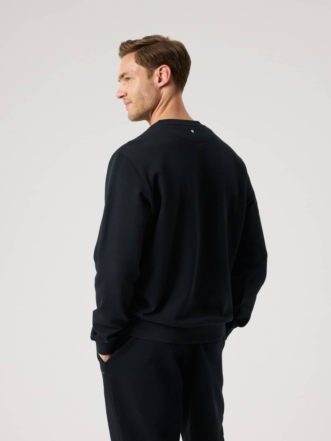 Back view of a man wearing the cotton Borg Classic Sweatshirt in Black Beauty (Black) with a white tennis ball logo. - Image 2