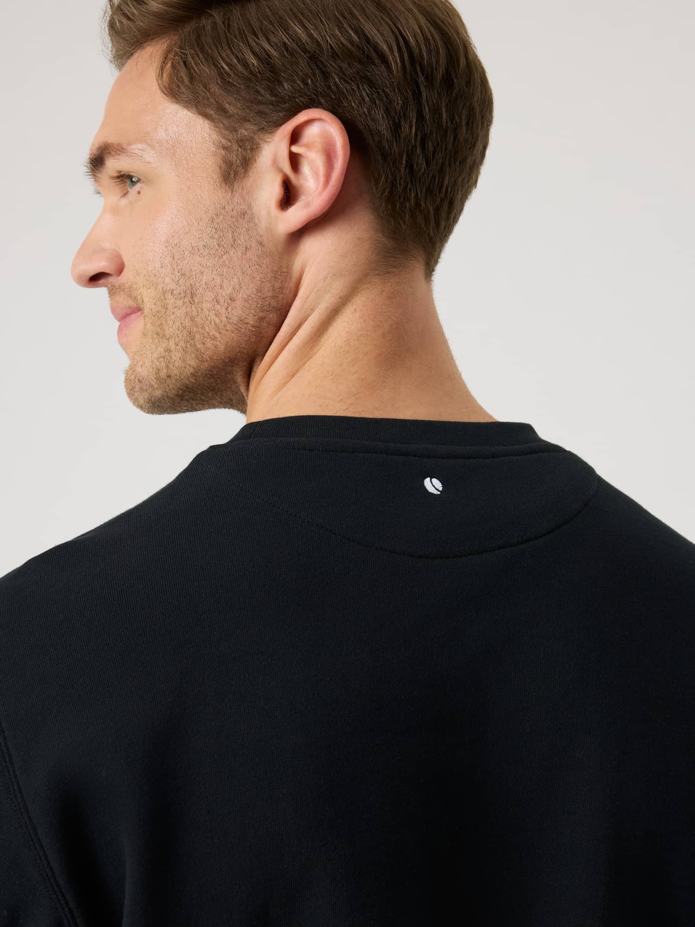 Detailed back neck view of the Borg Classic Sweatshirt in Black Beauty (Black) featuring a white tennis ball logo. - Image 5
