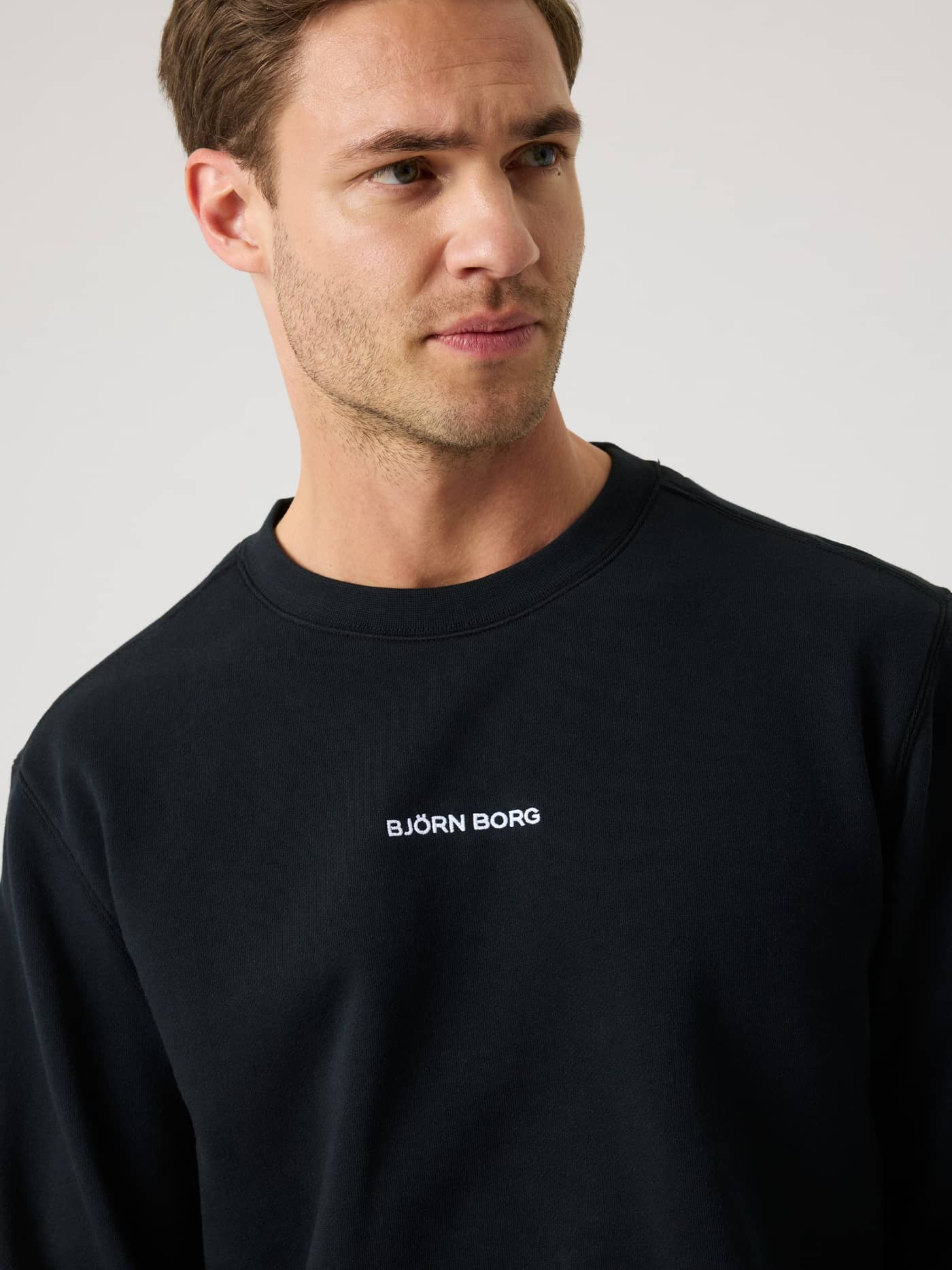 Close-up of a man wearing the stylish cotton Borg Classic Sweatshirt in Black Beauty (Black) with a white chest logo. - Image 4