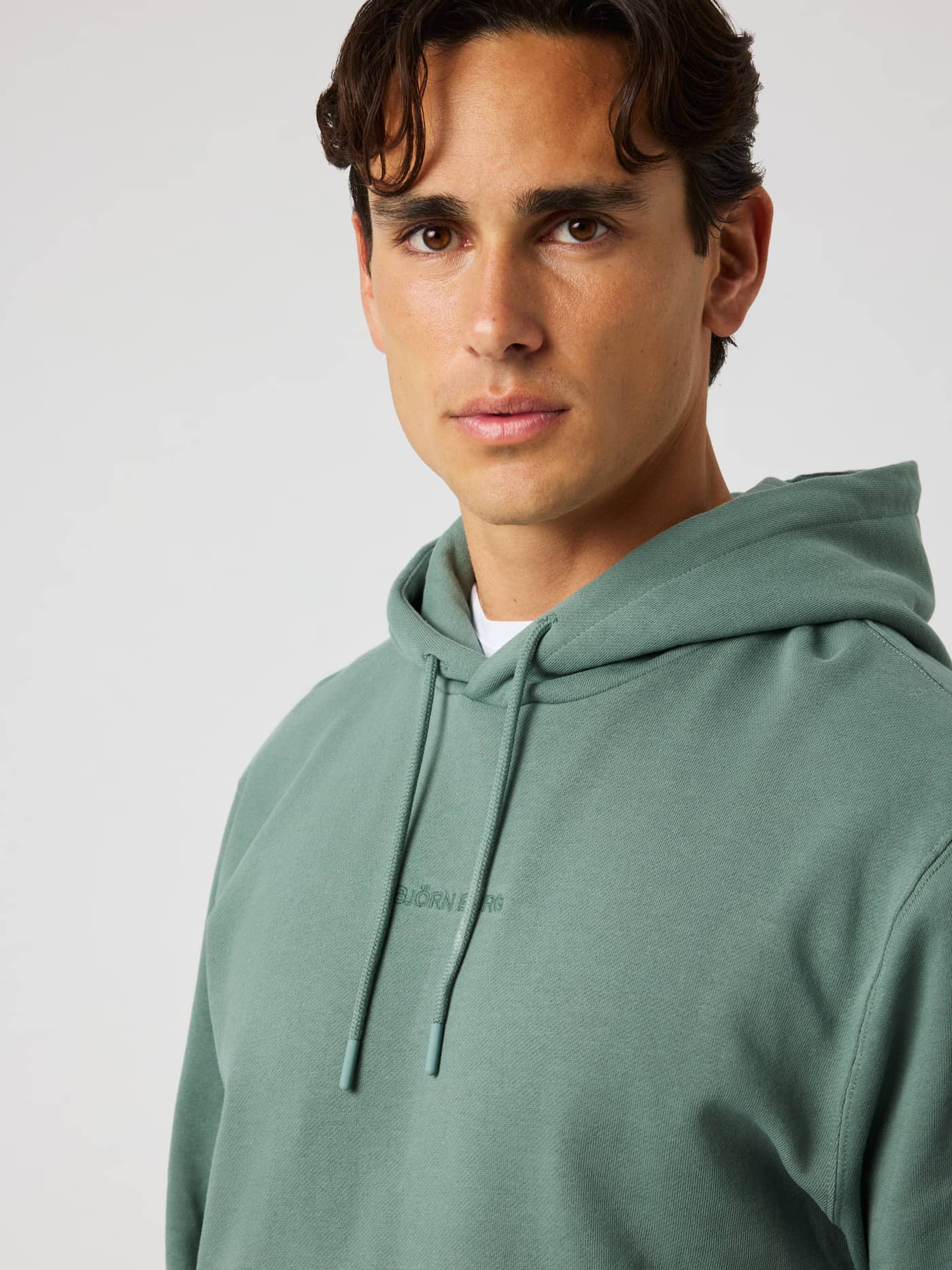 Close-up of the Borg Classic Hoodie in Laurel Wreath (green) featuring a matching green logo and adjustable drawstrings. - Image 3