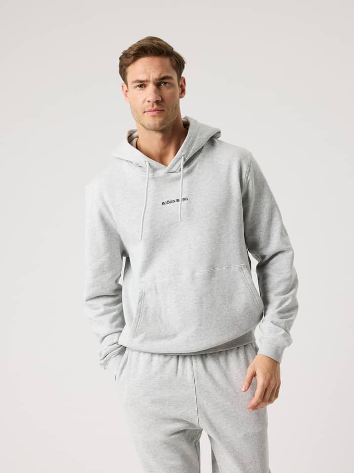 Front view of a man wearing the cotton Borg Classic Hoodie in Ultra Light Grey Melange (Grey) with black logo embroidery.