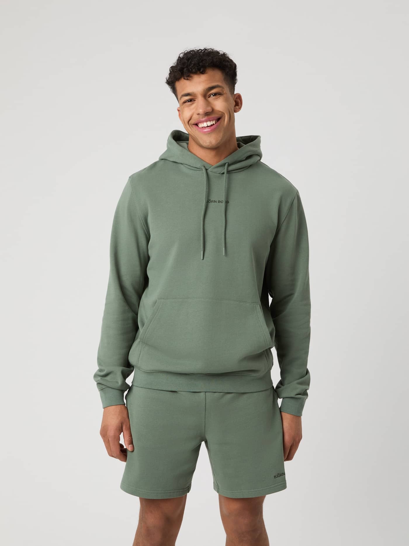 Vorderansicht eines Mannes im funktionalen Borg Classic Hoodie in Agave Green (Grün) mit schwarzem Logo aus 100 % Baumwolle. - Image 1