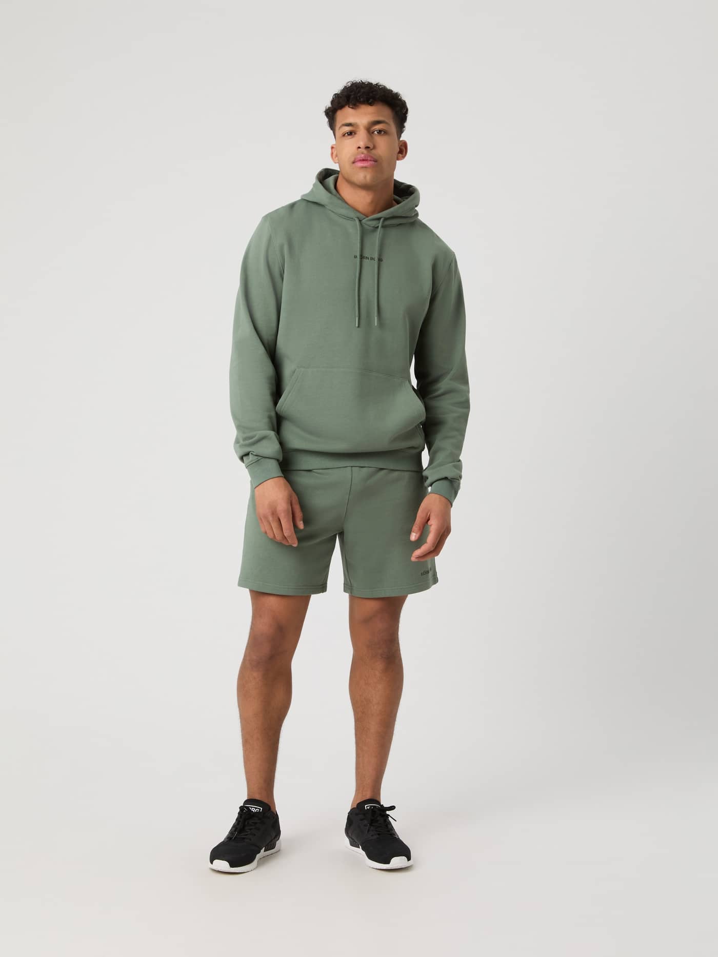 Ganzkörper-Vorderansicht eines Mannes im stilvollen Borg Classic Hoodie in Agave Green (Grün) mit schwarzem Logo. - Image 3