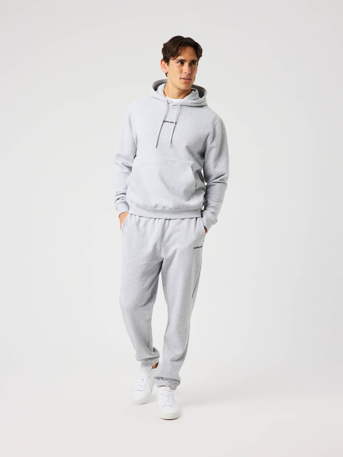 Man wearing the Borg Classic Hoodie in light grey melange (grey) with a double-layered hood and front pocket. - Image 4