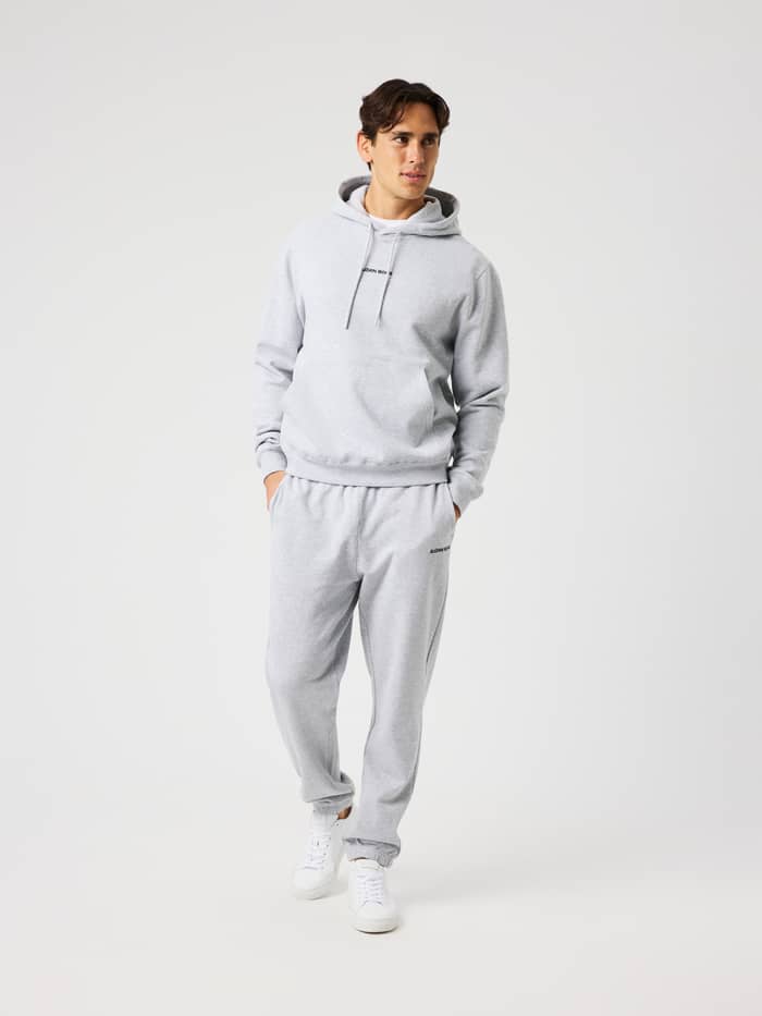 Man wearing the Borg Classic Hoodie in light grey melange (grey) with a double-layered hood and front pocket.