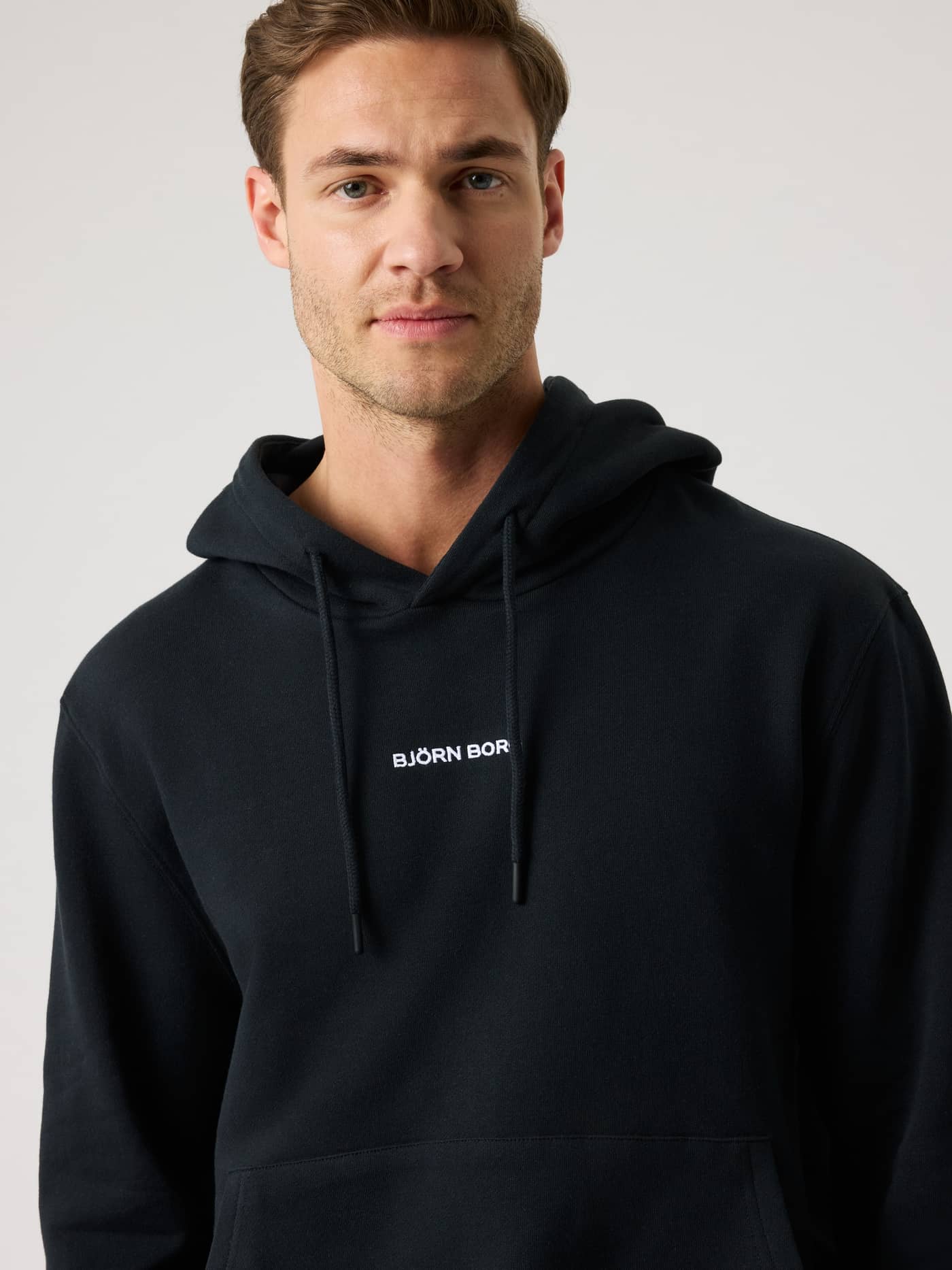 Front view of a man wearing the Borg Classic Hoodie in Black Beauty (Black) with white logo embroidery on French terry. - Image 6