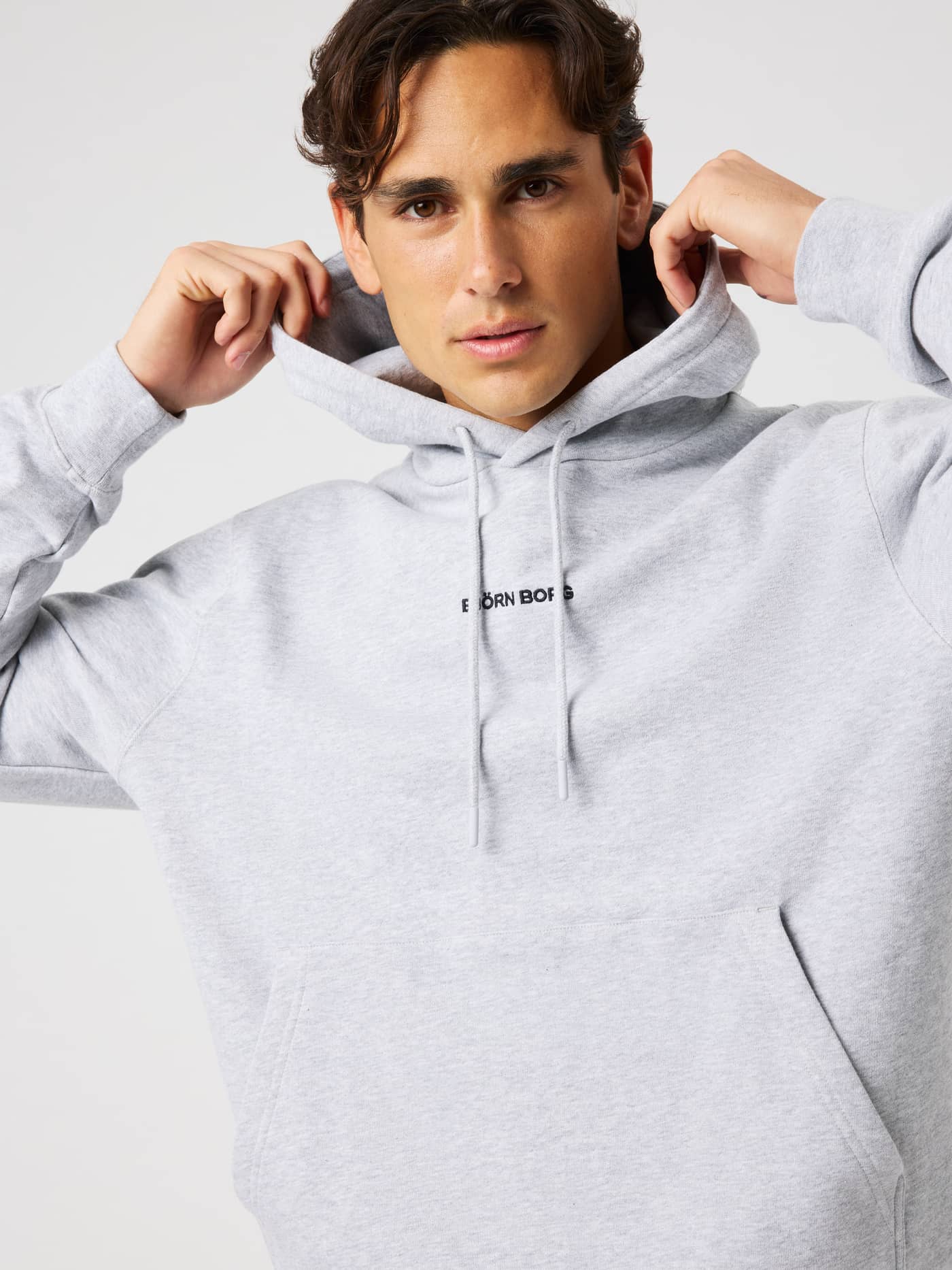 Close-up of the Borg Classic Hoodie in Light Grey Melange (grey) with an adjustable double-layer hood and front logo. - Image 1