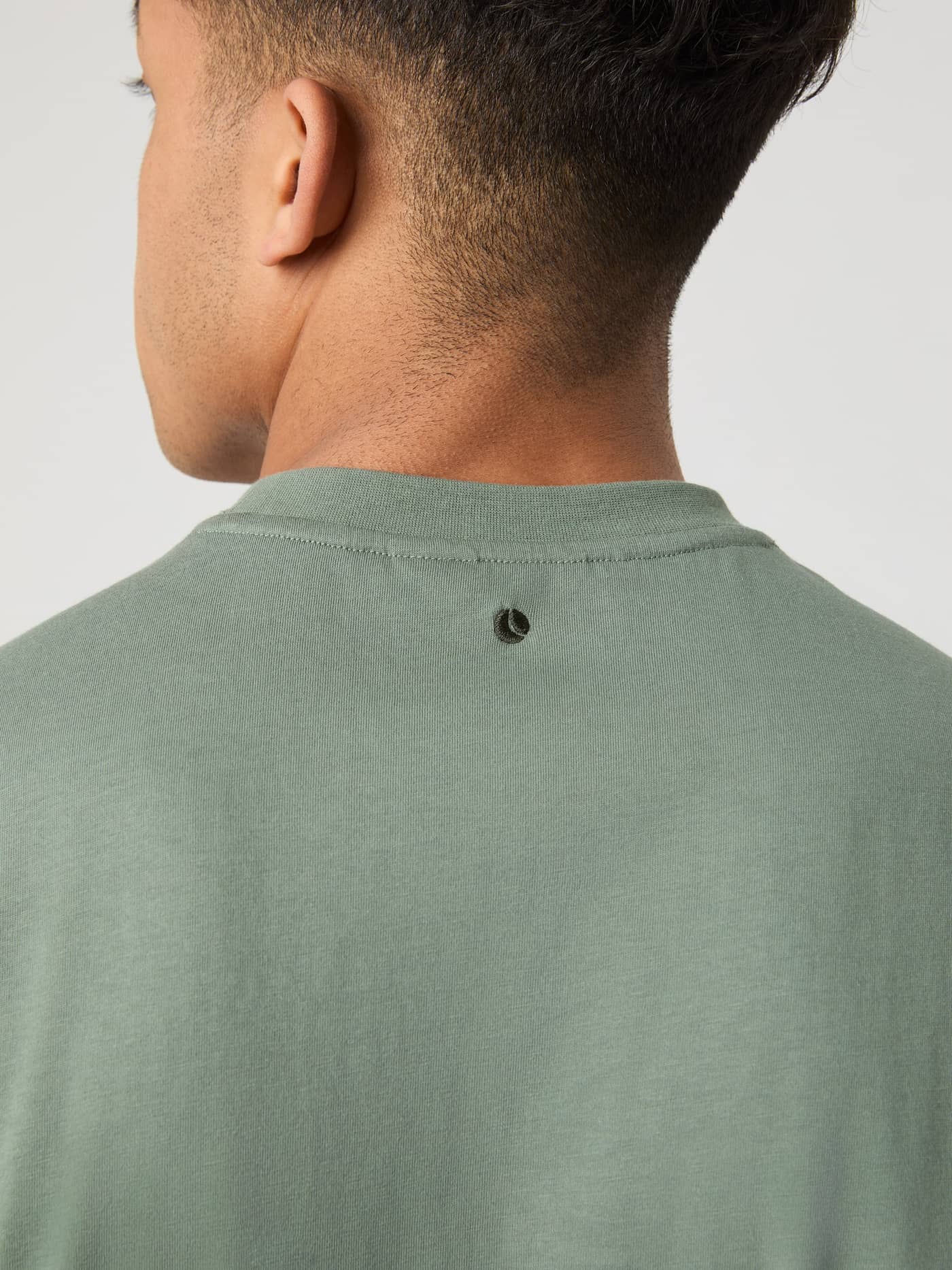 Gedetailleerd achteraanzicht van het katoenen Borg Classic T-Shirt in Agave Green (Groen) met zwart geborduurd tennisballogo. - Image 5