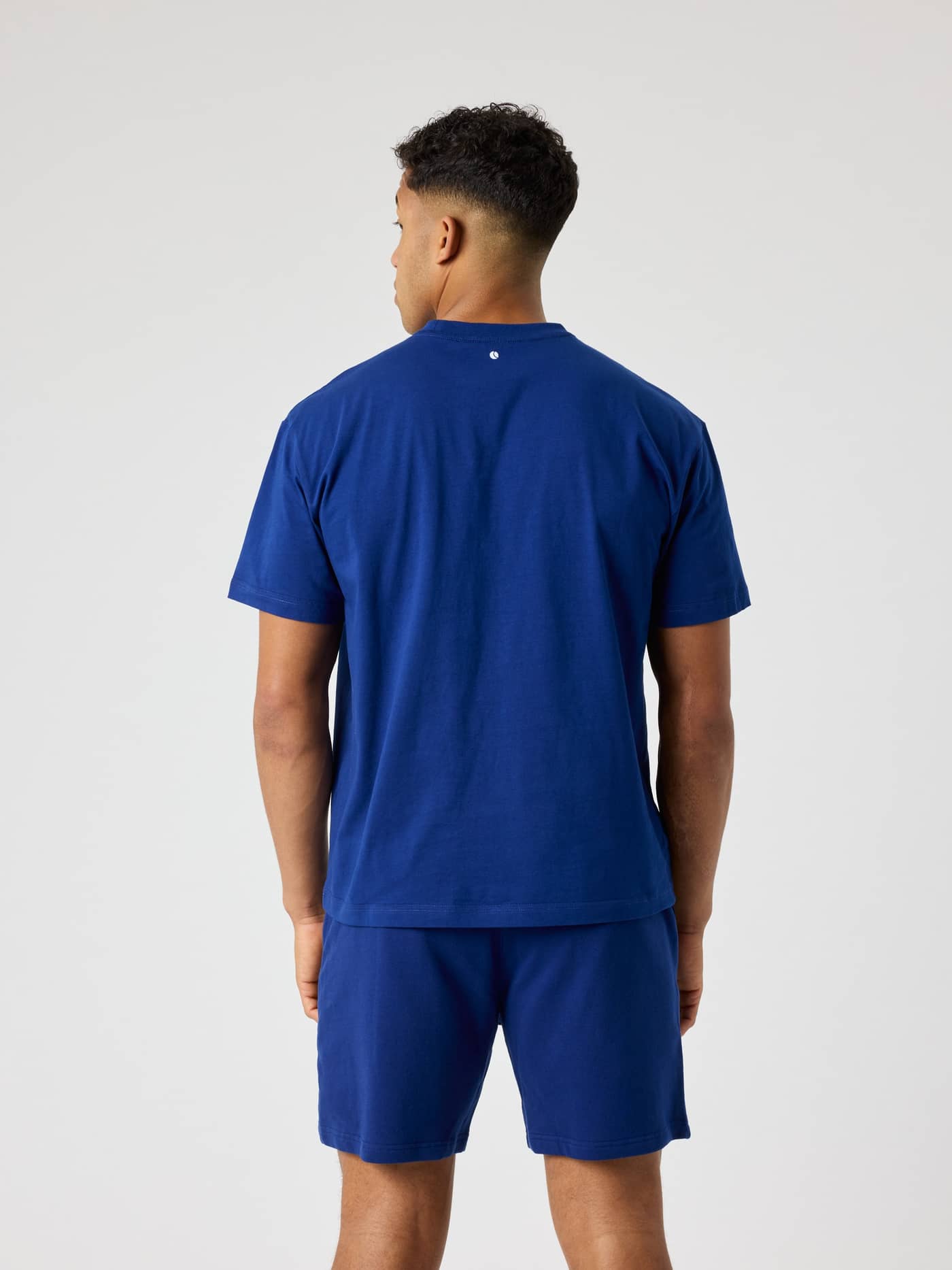 Rückansicht eines Mannes im Borg Classic T-Shirt in Blue Depths (Blau) aus Baumwolle mit Tennisball-Logo-Detail. - Image 2
