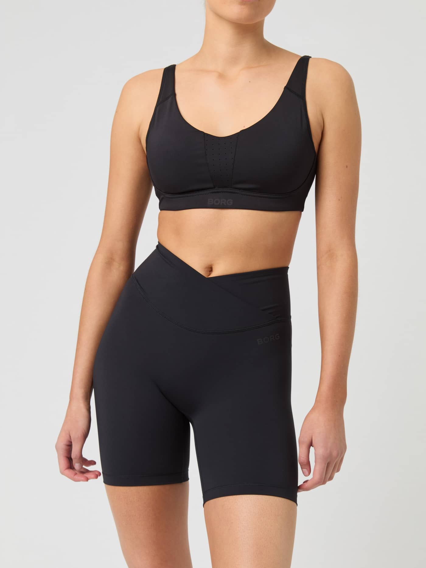 Vue de face d'une femme en Studio Cross Shorts Black Beauty (Noir) avec taille croisée pour l'entraînement. - Image 1