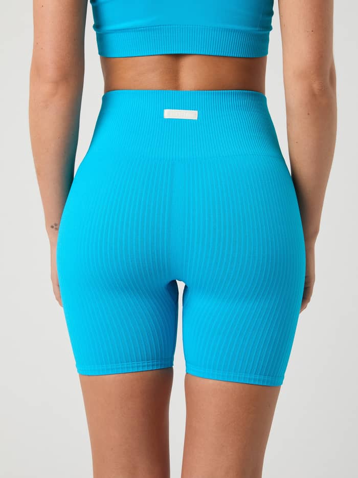 Back view of the Studio Seamless Ribbed Shorts in Atomic Blue (Blue) with a seamless fit for training and white logo label. - Image 4