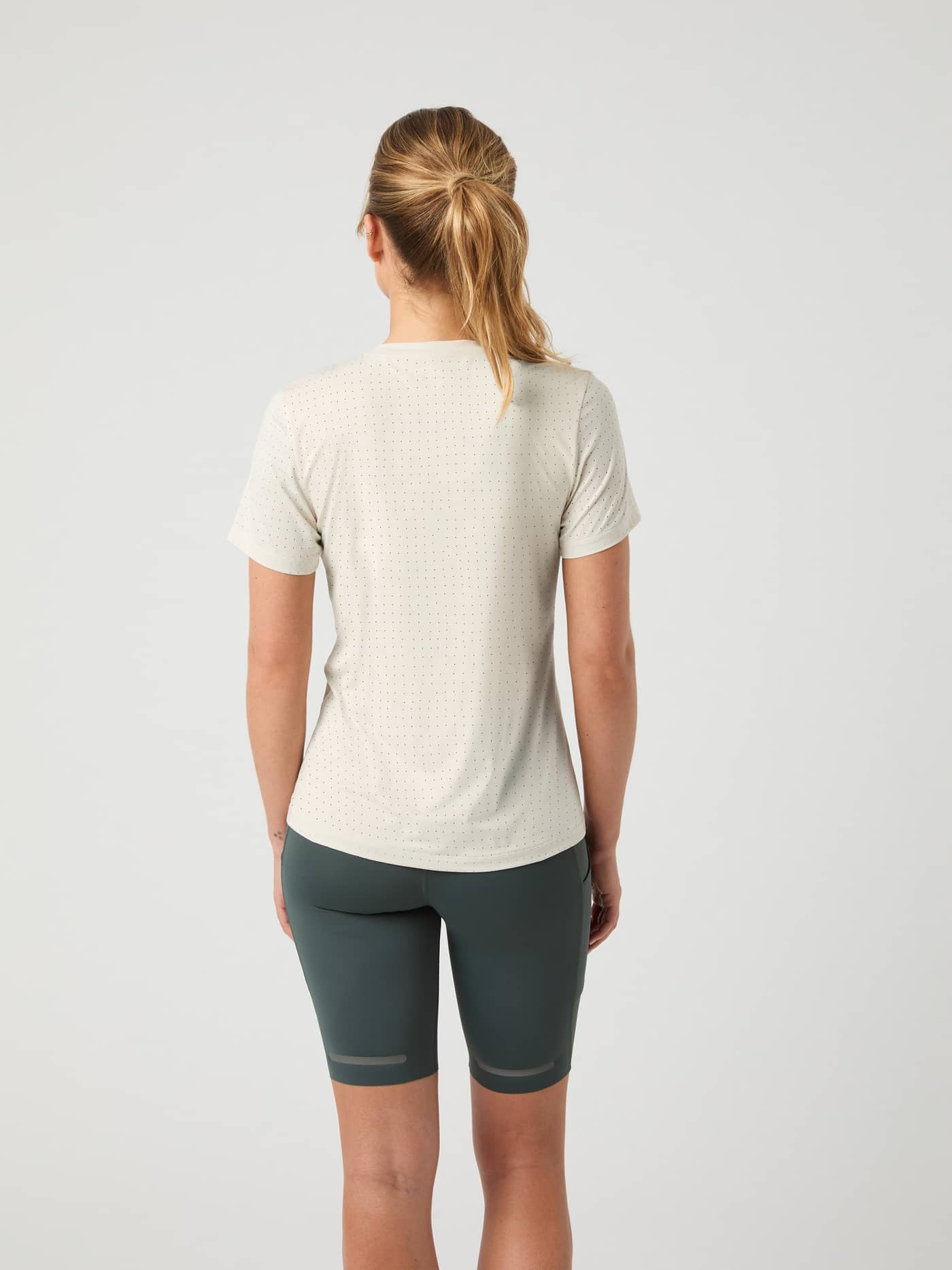 Back view of a woman wearing the Borg Running Perforated T-Shirt in Birch (White), featuring a breathable athletic fit. - Image 2
