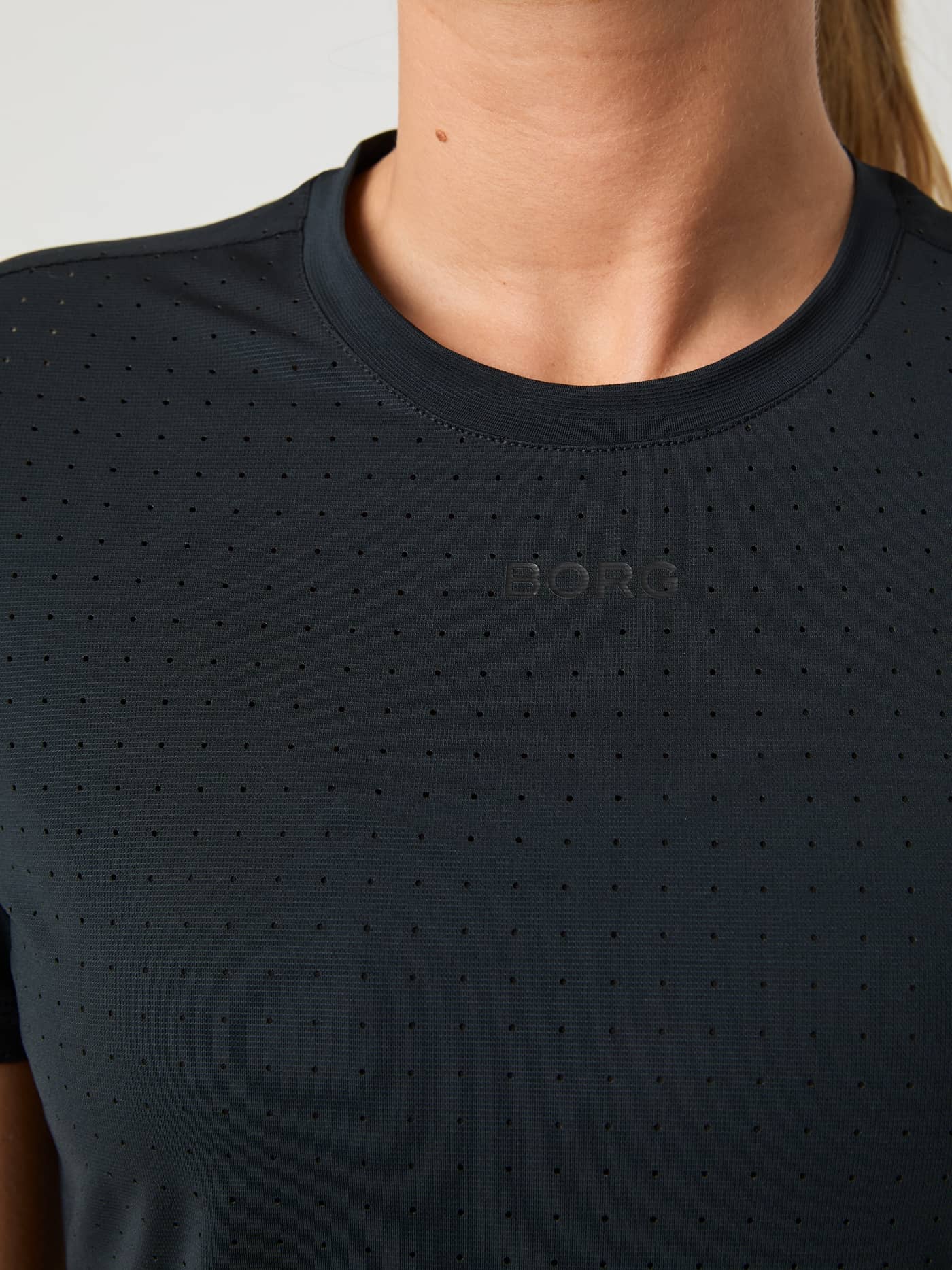 Close-up van het Borg Performance Perforated T-Shirt in Black Beauty (Zwart), een hardloopshirt met een zwart logo. - Image 4