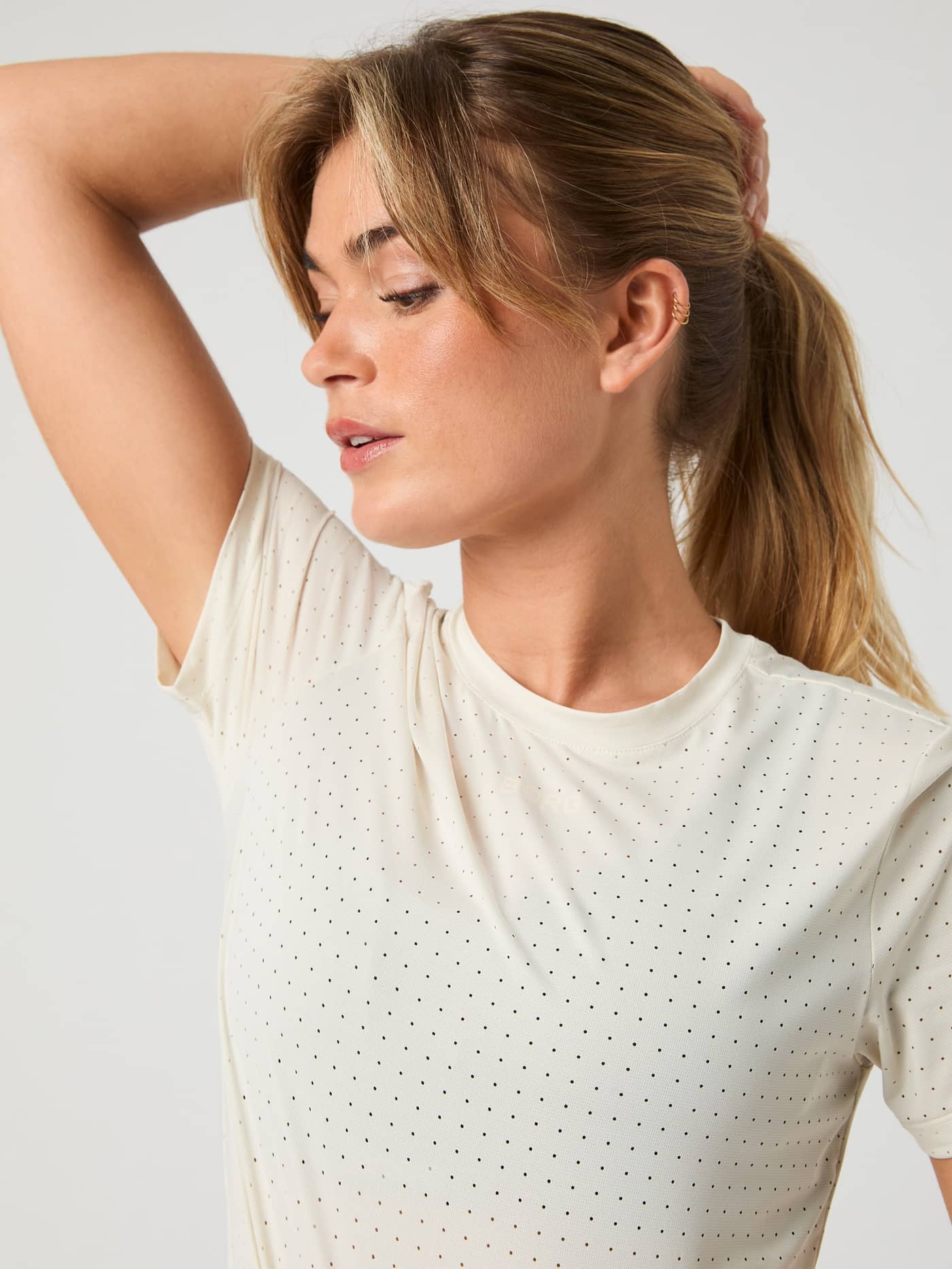 Close-up side view of a woman in the breathable Björn Borg Running Perforated T-Shirt in Birch (White). - Image 3