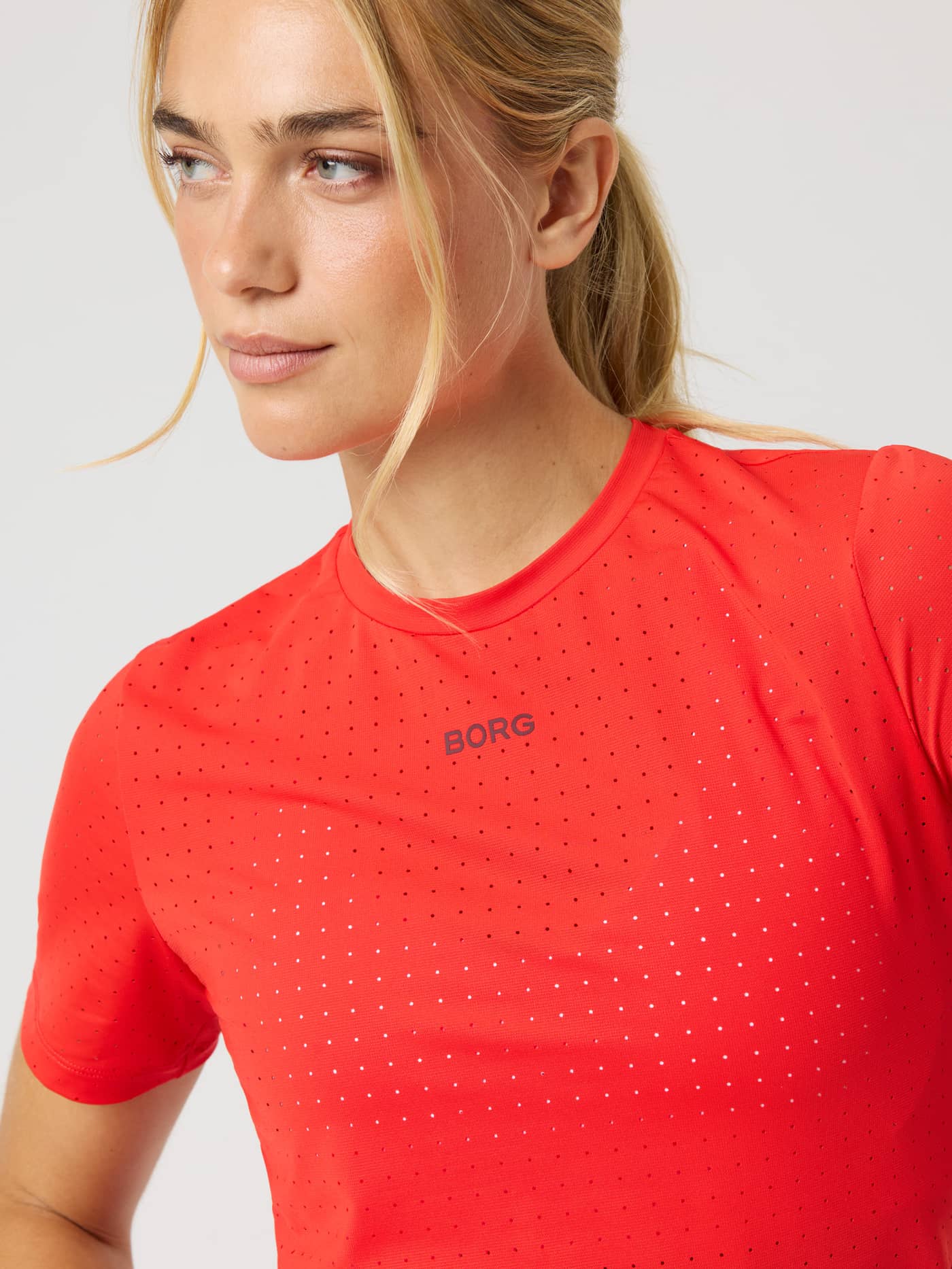 Close-up of the Borg Performance Perforated T-Shirt in Flame Scarlet (Red) with a black chest logo for running. - Image 5