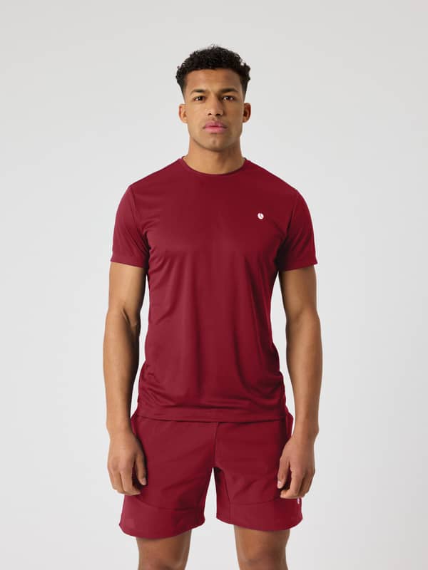 Mannelijk model draagt het Cabernet Ace Light T-Shirt in rood (Rood) met een wit logo voor tennis.