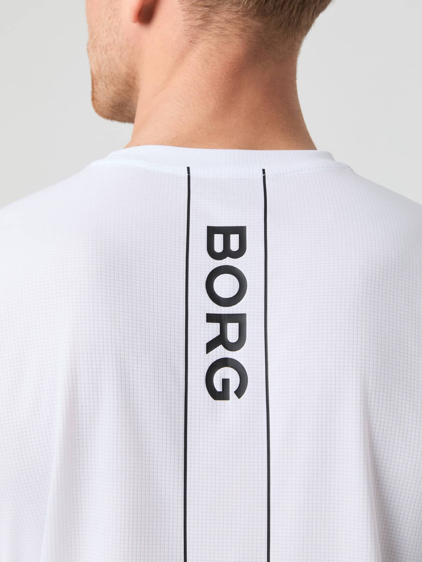 Ace Light T-Shirt i Brilliant White (Hvid) set bagfra i nærbillede med sort logostribe til tennis. - Image 5
