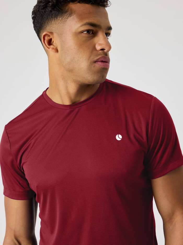 Close-up of the Ace Light T-Shirt in Cabernet (red) highlighting the breathable performance fabric and white logo for tennis.