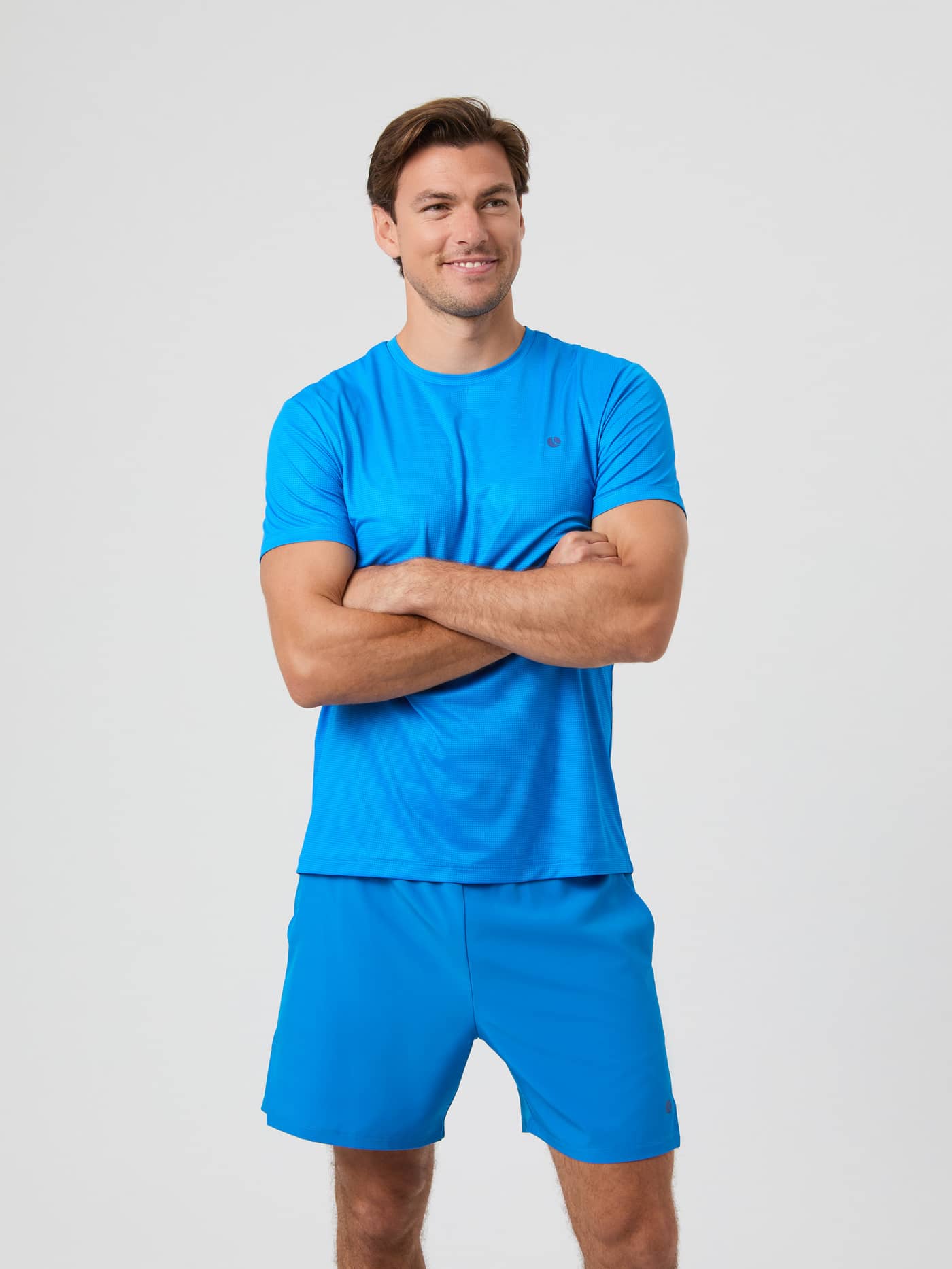Front view of a male model wearing the electric blue Björn Borg Ace Light T-shirt and matching shorts, with arms crossed. - Image 1