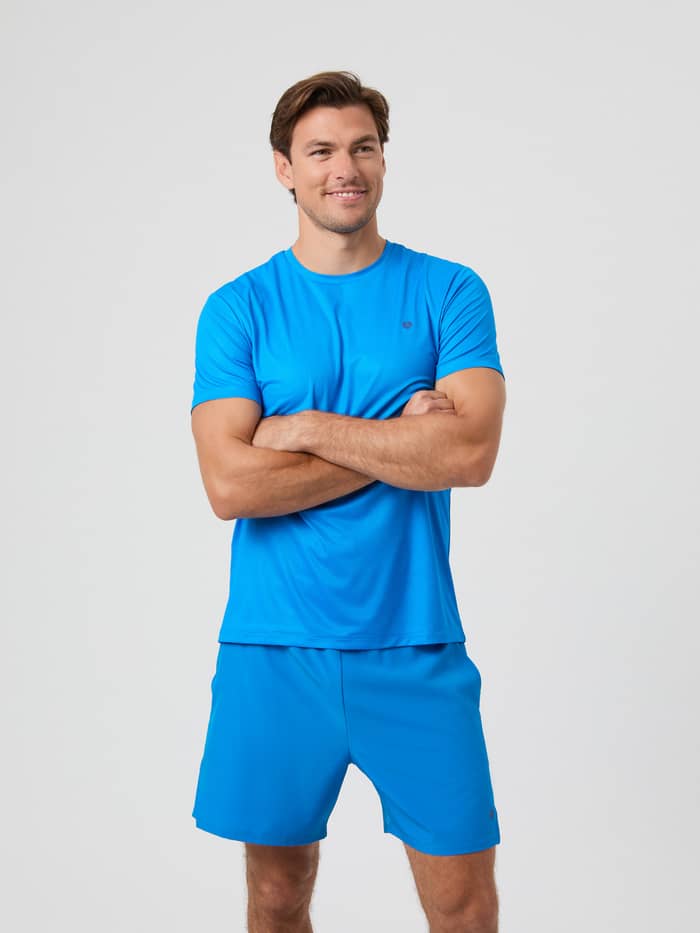 Front view of a male model wearing the electric blue Björn Borg Ace Light T-shirt and matching shorts, with arms crossed.