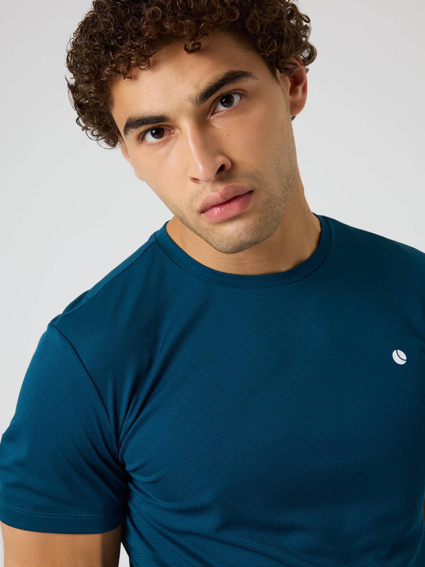 Close-up of a model wearing the Ace Light T-Shirt in Reflecting Pond (Green) for tennis with a white chest logo. - Image 5