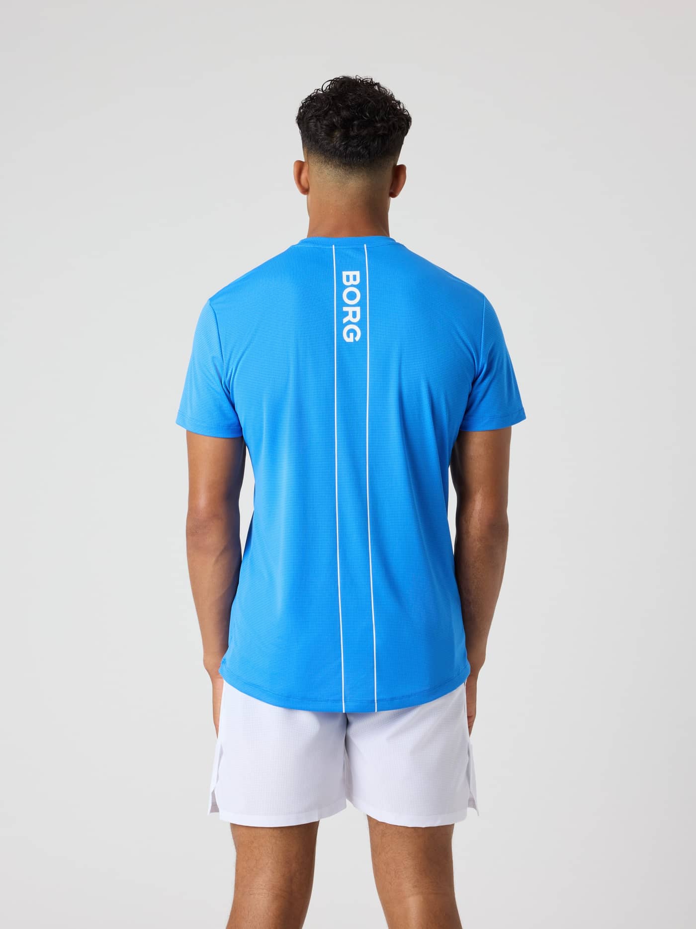 Back view of a model wearing the Björn Borg Ace Light T-Shirt in Palace Blue (Blue) with white logo and tennis court lines. - Image 2