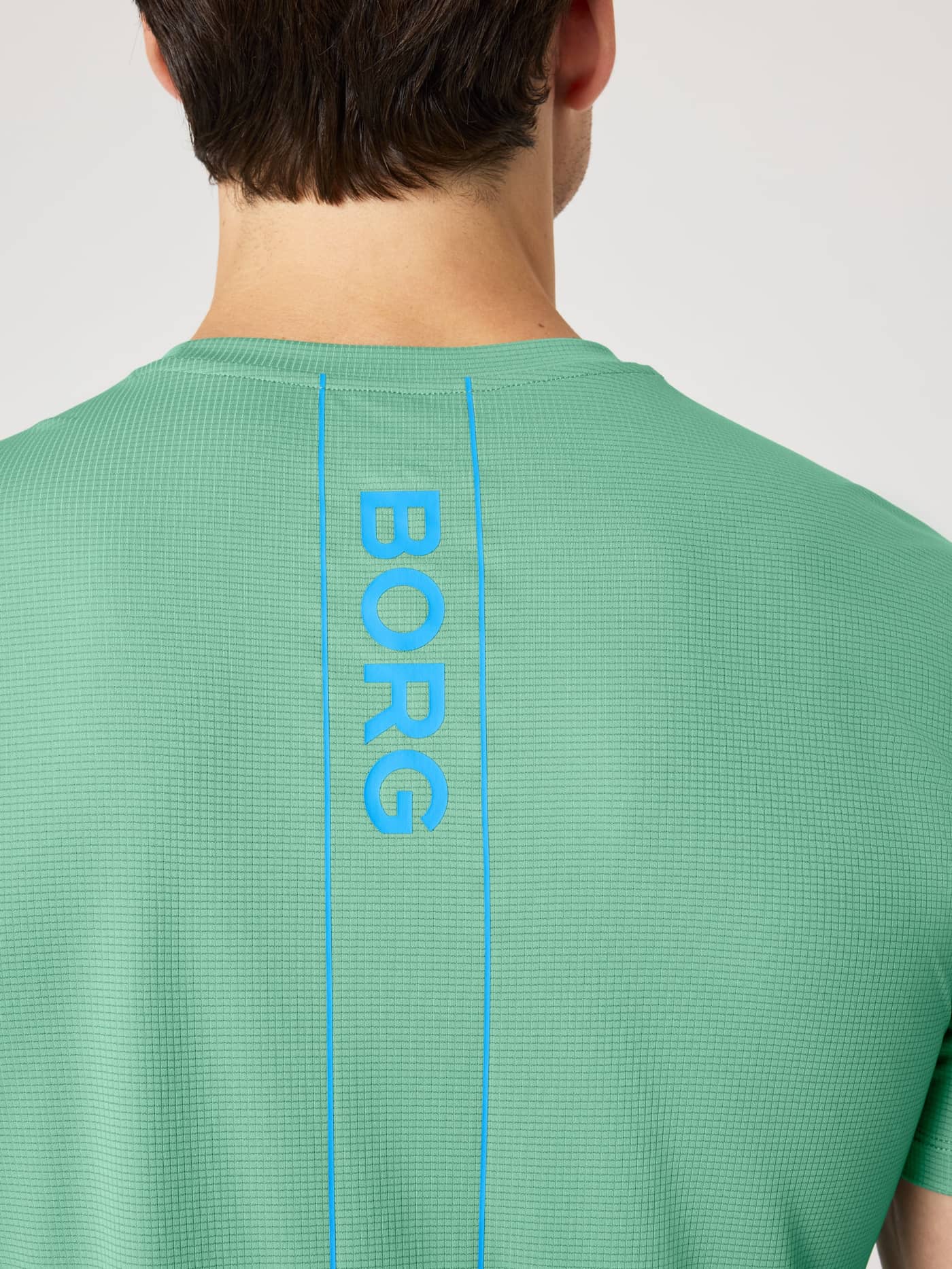 Close-up back view of the breathable Ace Light T-Shirt in Malachite Green (Green) with blue Borg tennis court lines. - Image 4