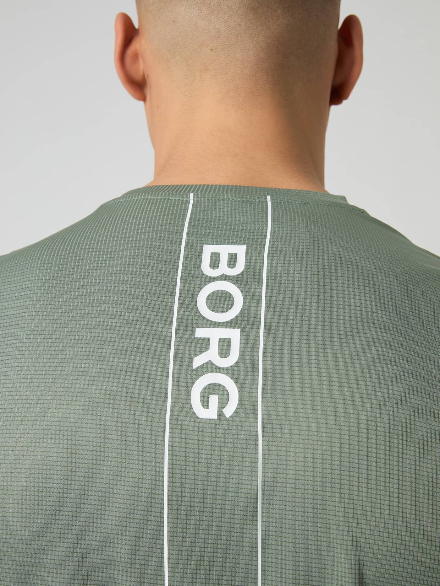 Close-up of the vertical BORG logo on the back of the Björn Borg Ace Light T-shirt in Agave Green. - Image 4