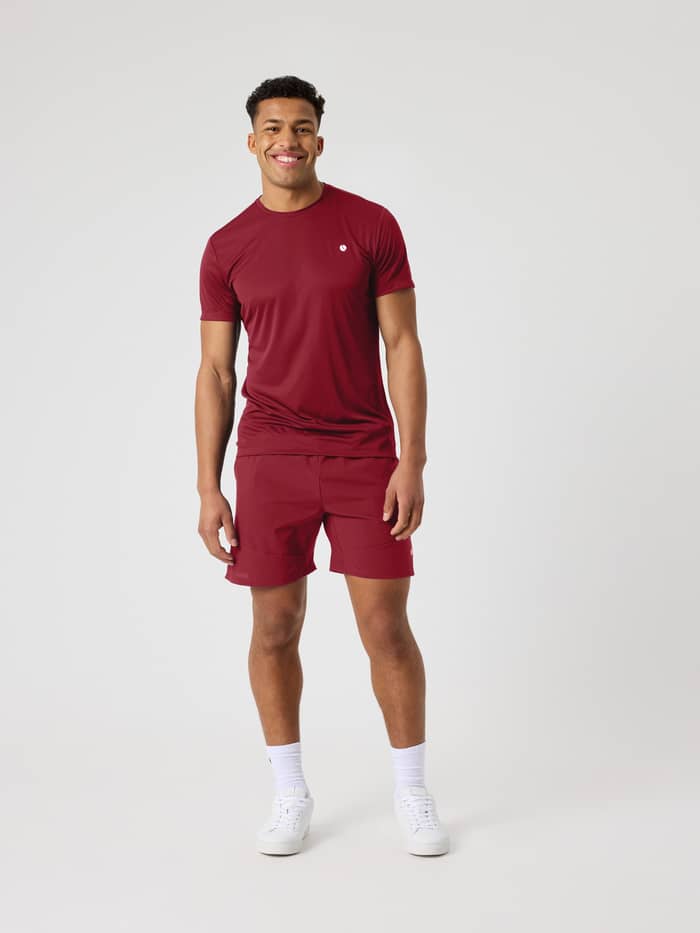 Male model wearing the Ace Light T-Shirt in Cabernet (red) for tennis.