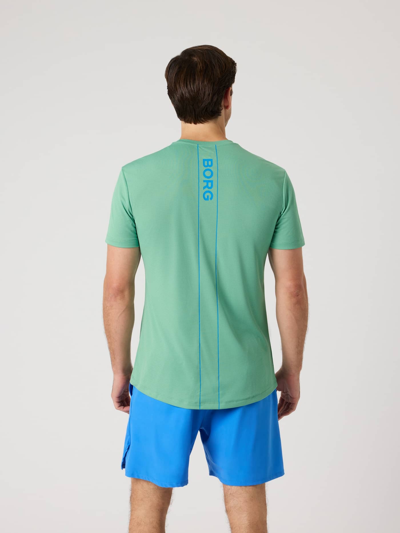 Back view of a man wearing the Björn Borg Ace Light T-Shirt in Malachite Green (Green) with a blue logo stripe for tennis. - Image 2
