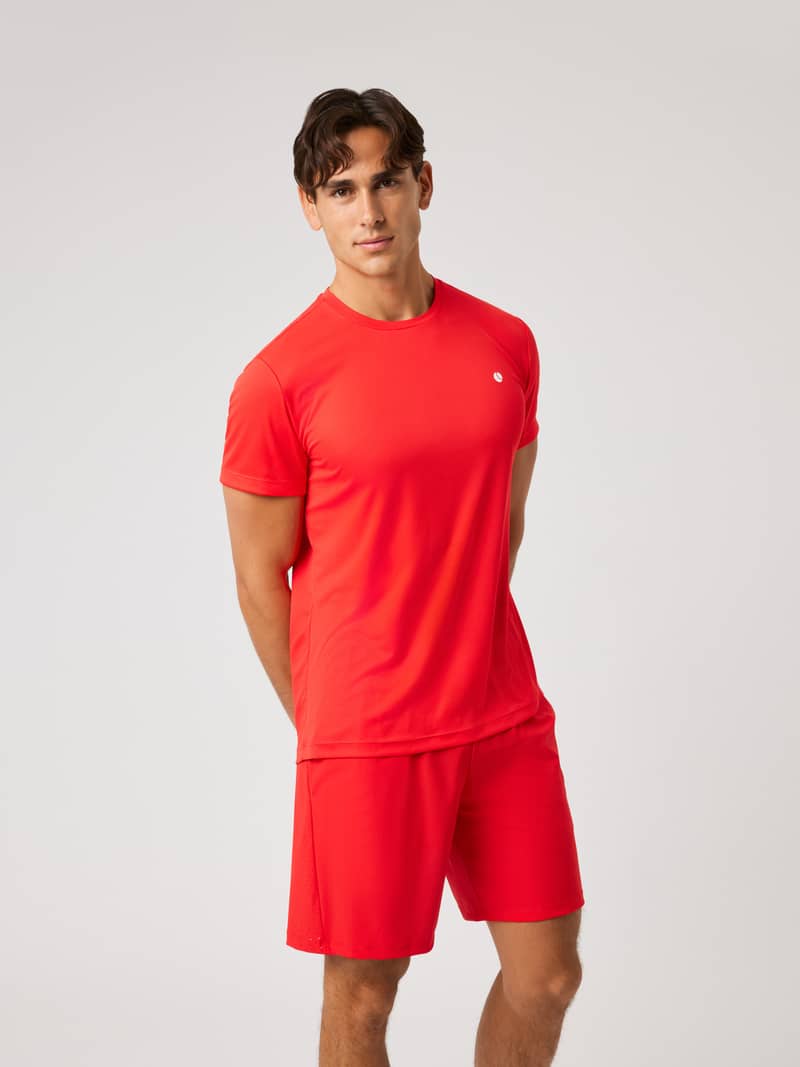 Vooraanzicht van een man in het Ace Light T-Shirt in Flame Scarlet (Rood) voor tennis met een klein wit borstlogo.