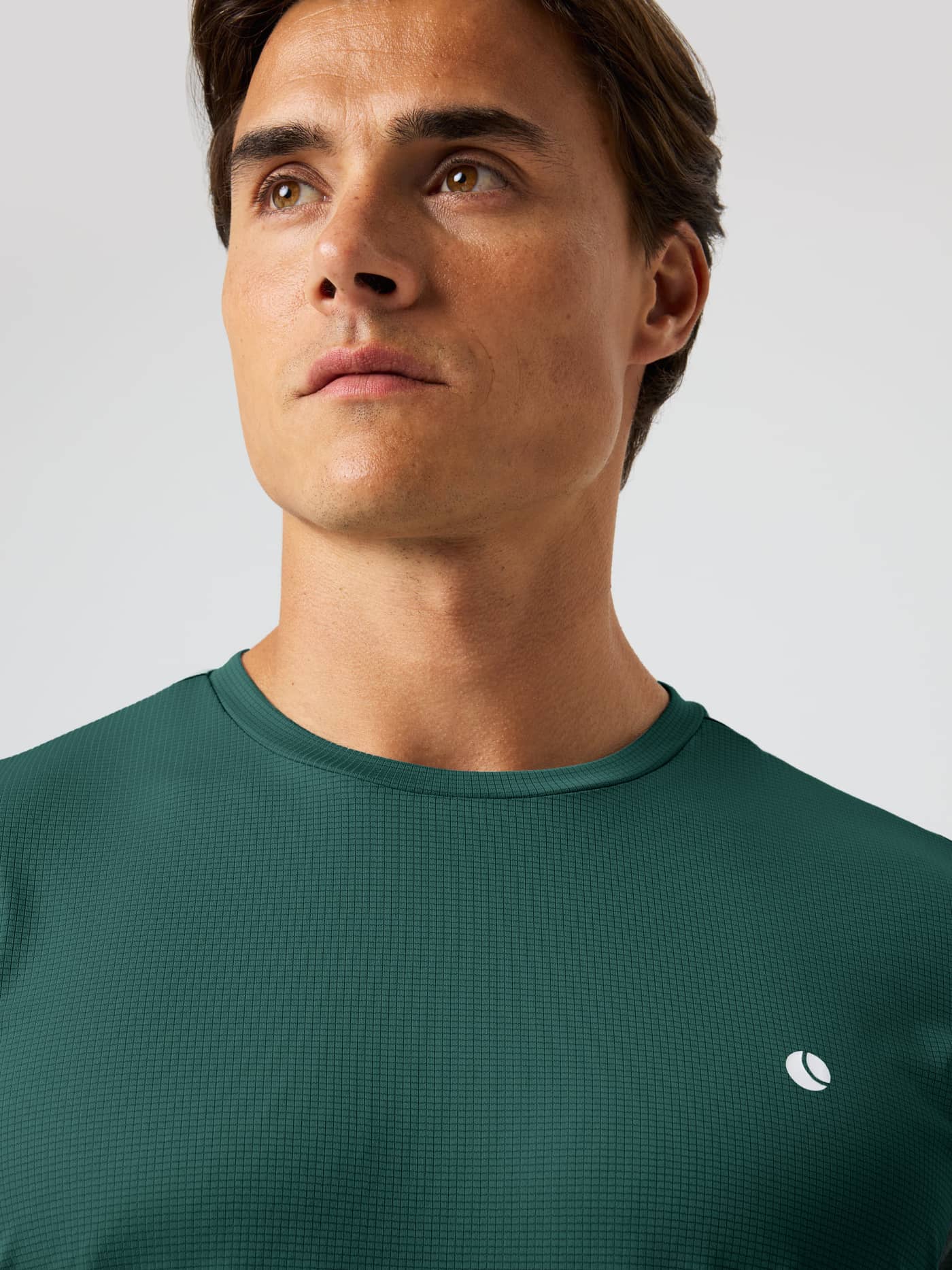 Close-up of the Ace Light T-Shirt in Mallard Green (Green) with a white tennis ball logo and breathable grid texture. - Image 4