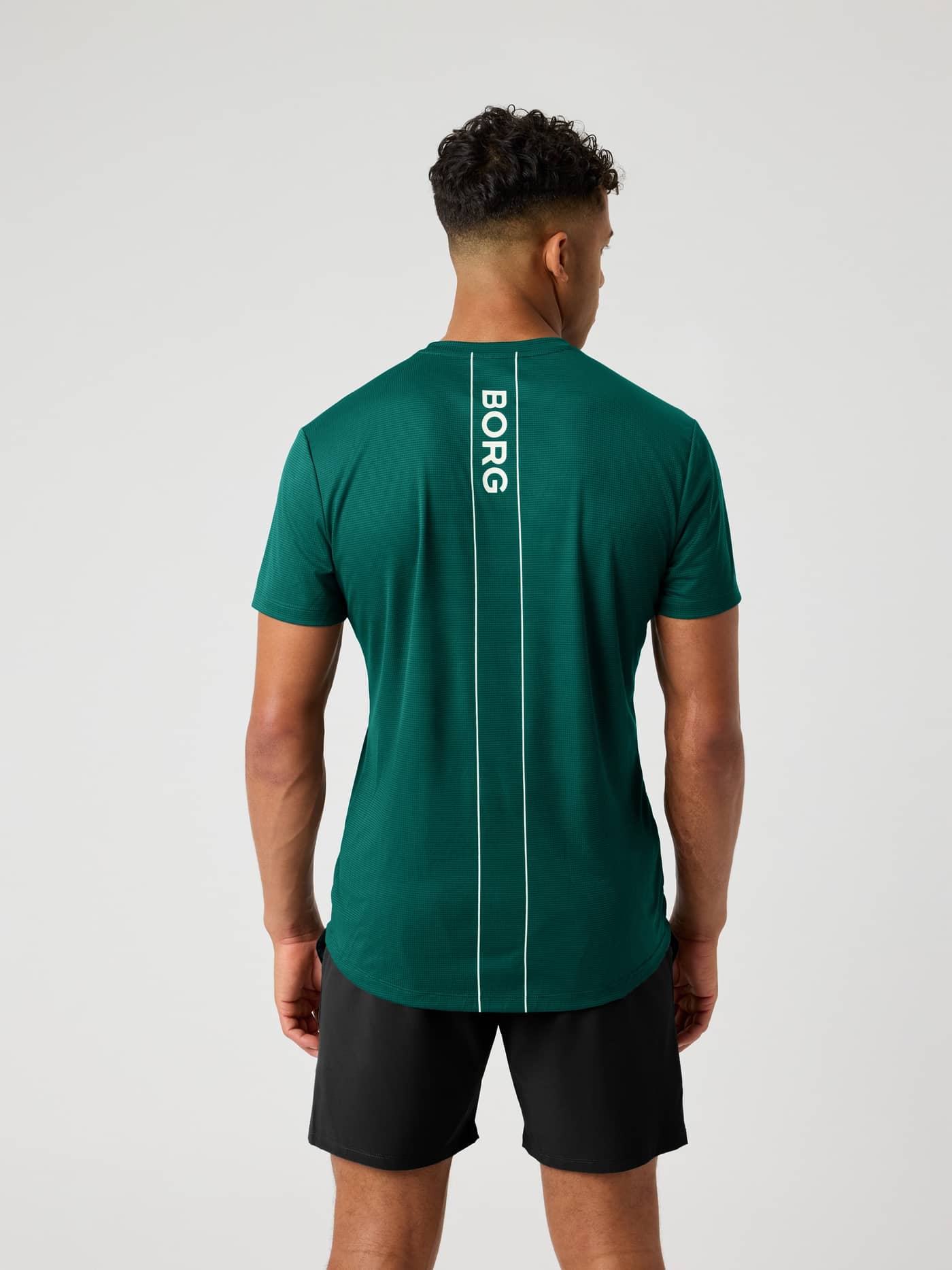 Vista posterior de la Ace Light T-Shirt en Posy Green (Verde) con banda de logo blanca para rendimiento en tenis. - Image 2