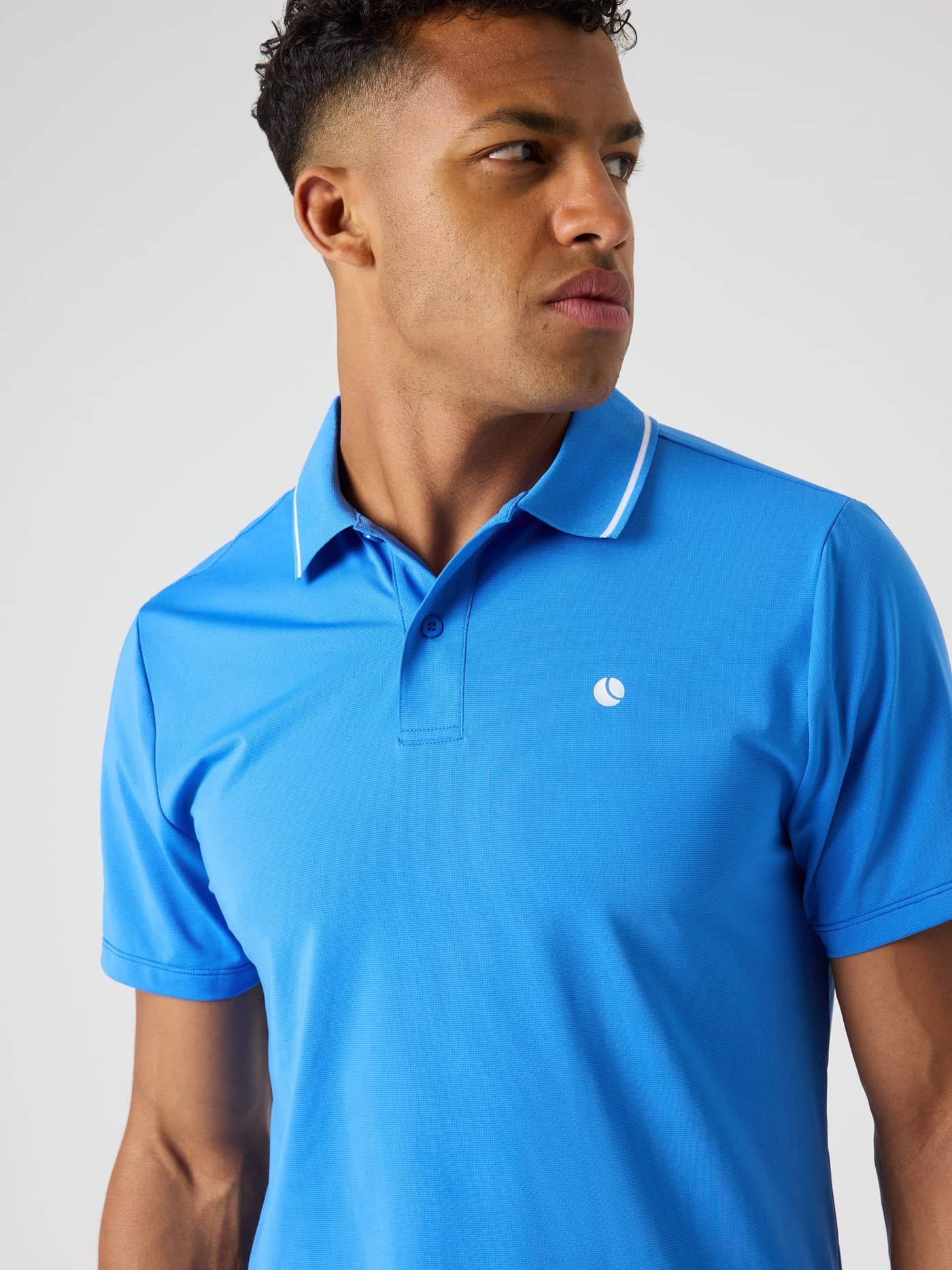 Close-up of a man wearing the Björn Borg Ace Polo Shirt in Palace Blue (Blue), a breathable tennis style with a logo. - Image 5