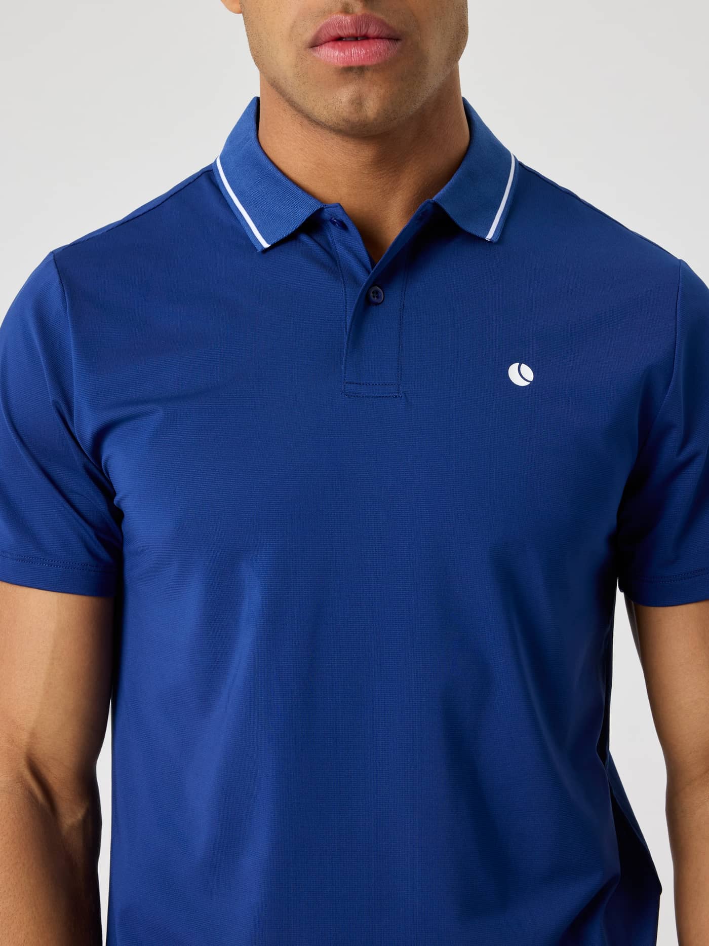 Närbild framifrån på en man i Ace Polo Shirt i Blue Depths (Blå) för tennis med en vit tennisbollslogotyp. - Image 5